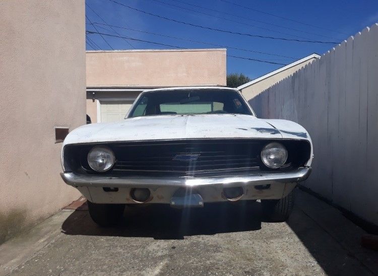 A white chevrolet camaro is parked in a driveway