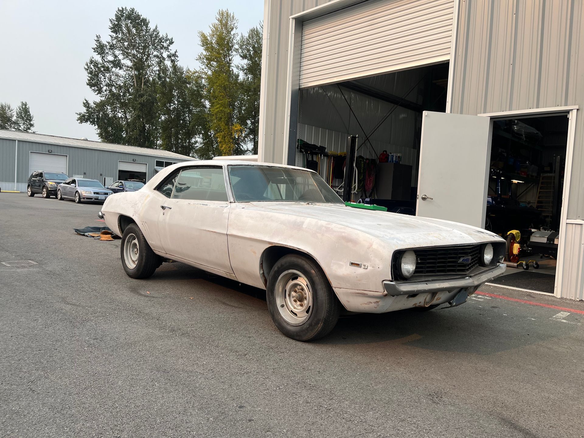 A white car is parked in front of a garage door.