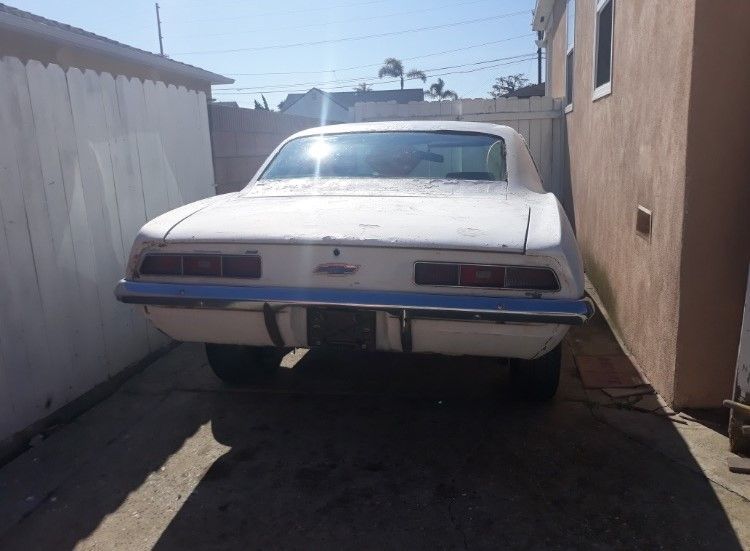 A white car is parked in a driveway next to a building