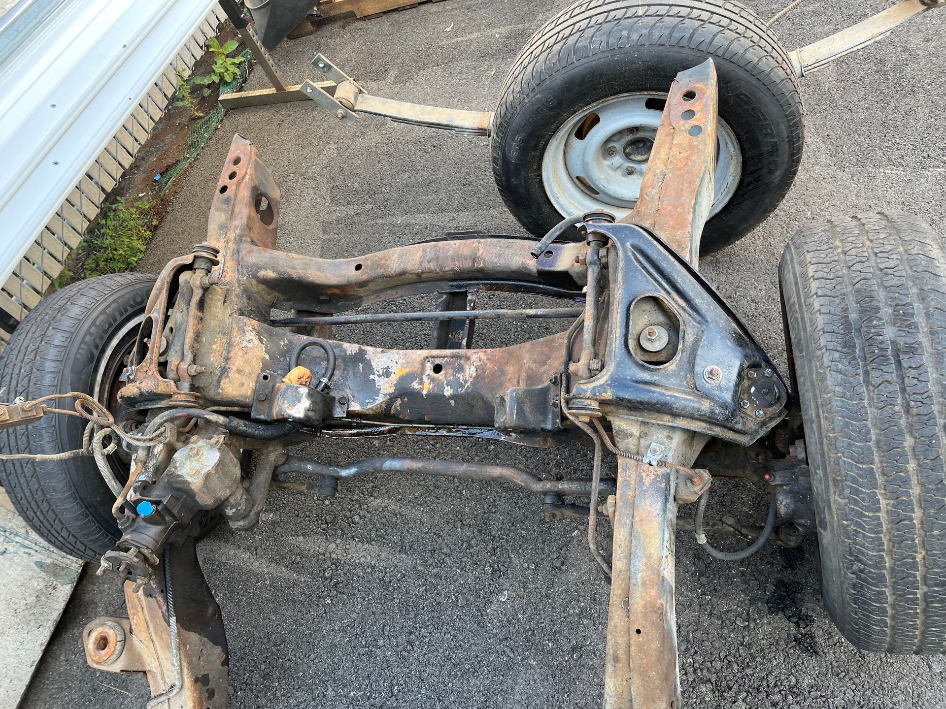 A car chassis is sitting on the ground next to a tire.