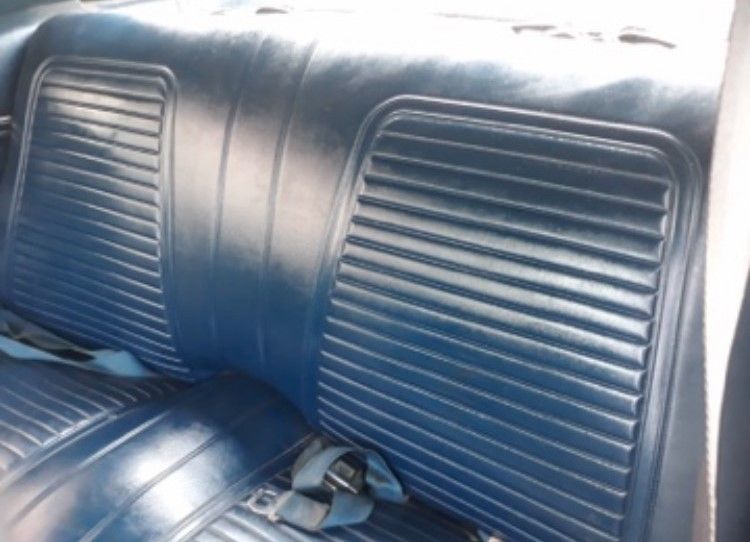 The back seat of a blue car with a seat belt