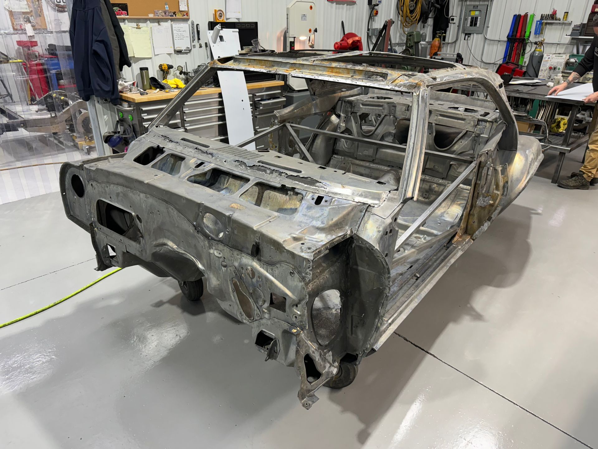 A car frame is sitting on the floor in a garage.