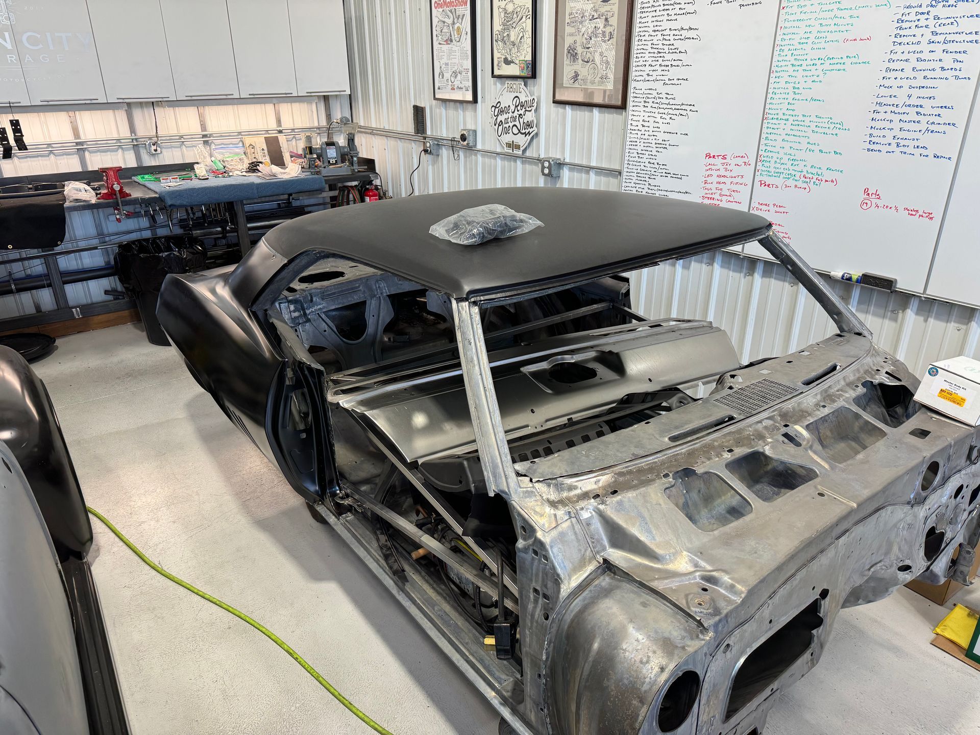 A car is being built in a garage with a white board in the background.