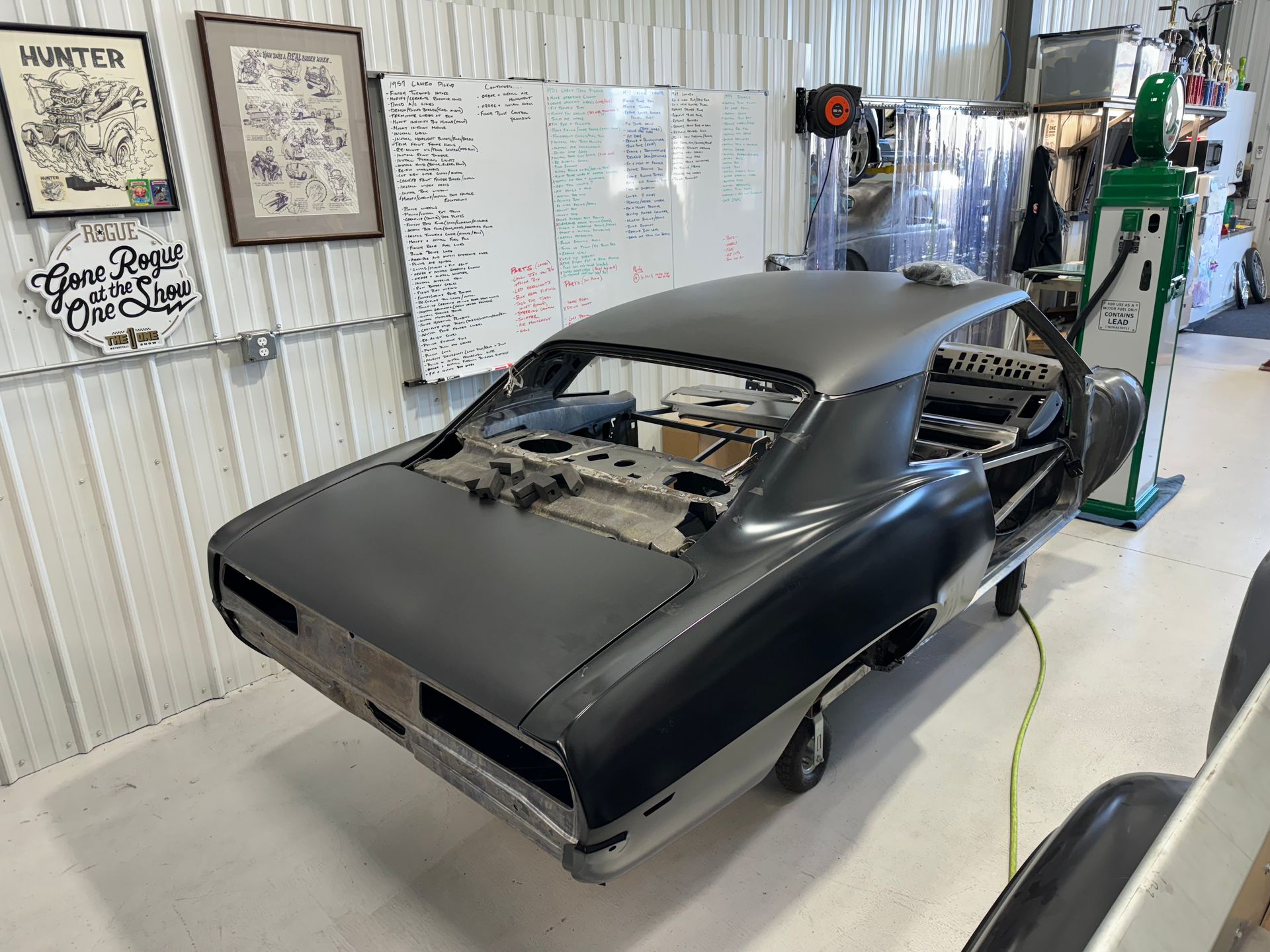 A black car is sitting in a garage next to a gas pump.