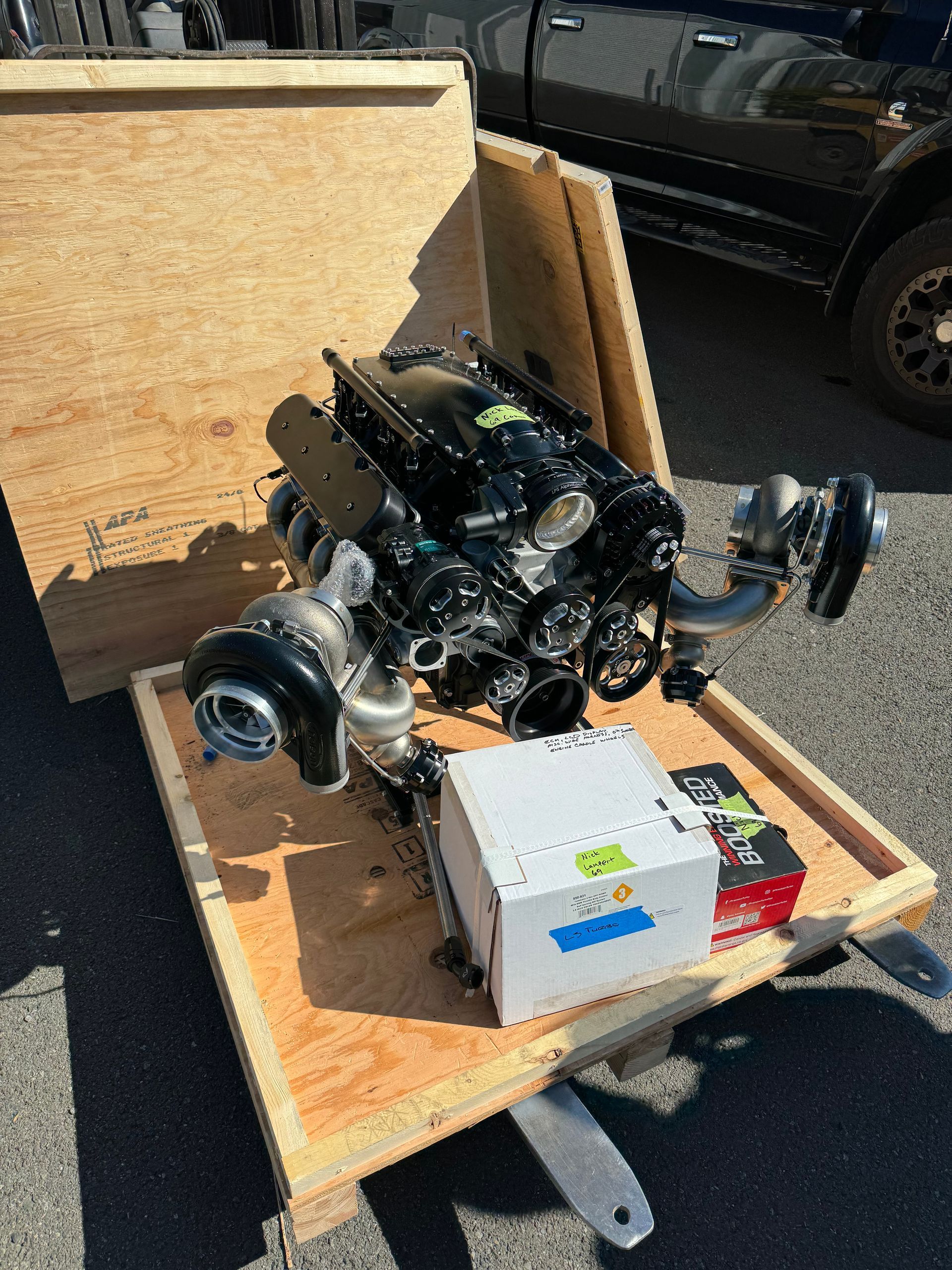 A black engine is sitting on top of a wooden box.