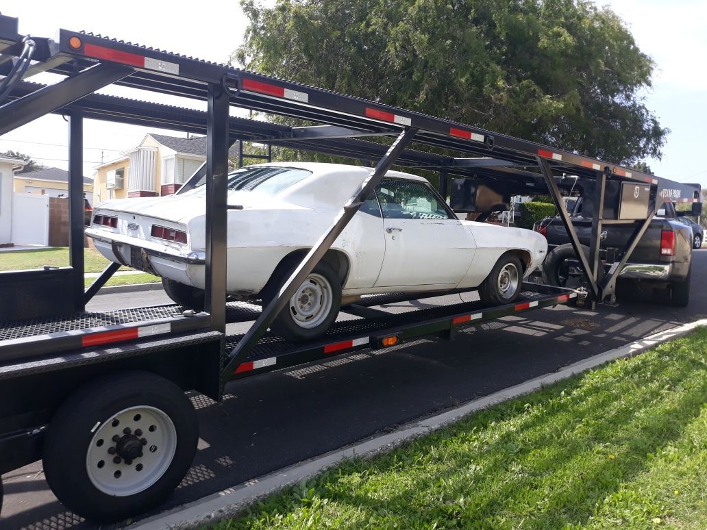 A white car is being transported on a trailer.
