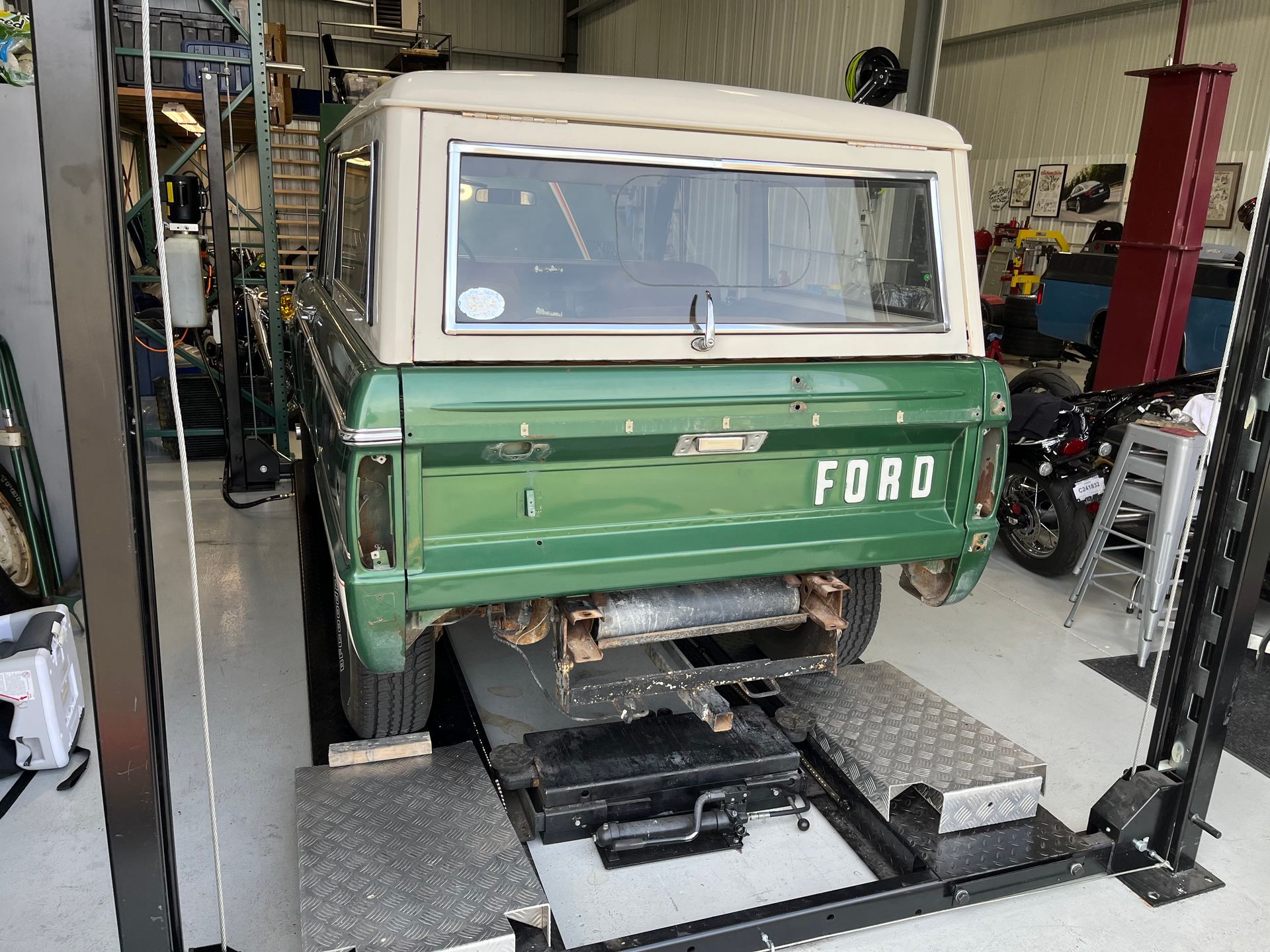 A green ford truck is sitting on a lift in a garage.