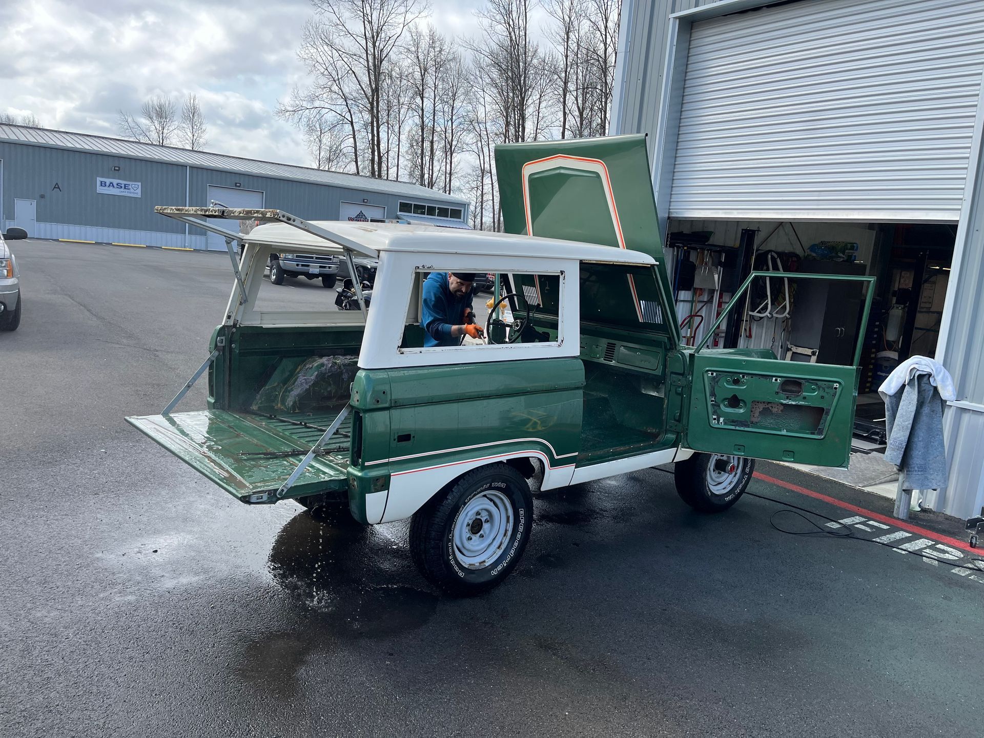 A green and white truck is parked in front of a garage door.