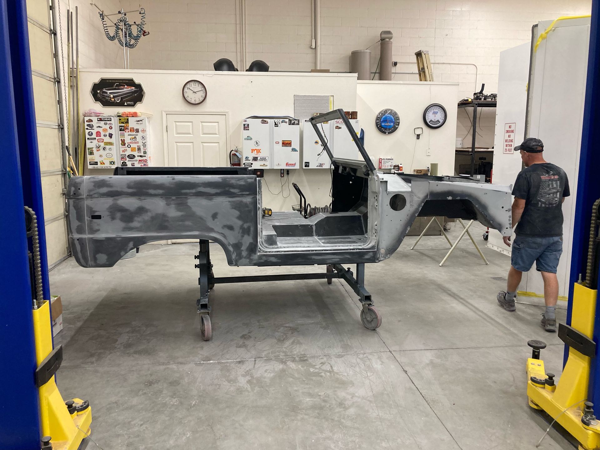 A man is working on a jeep body in a garage.
