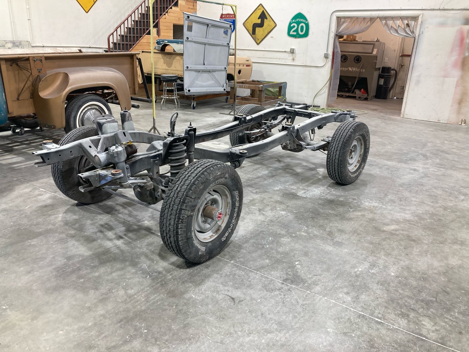 A truck chassis is sitting in a garage next to a sign that says 20.