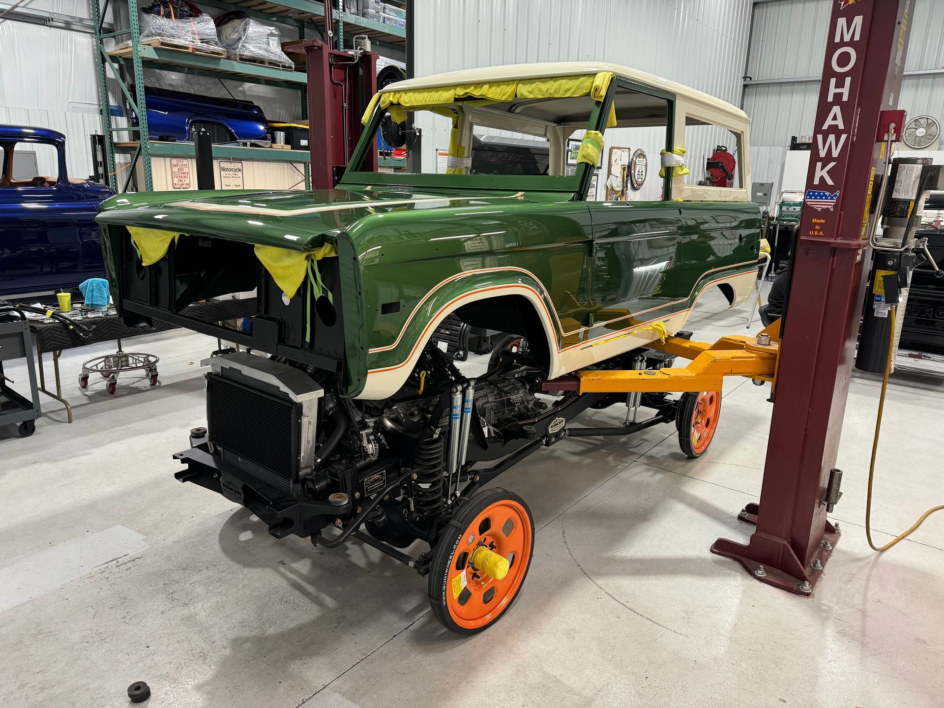 A green truck is sitting on a lift in a garage.