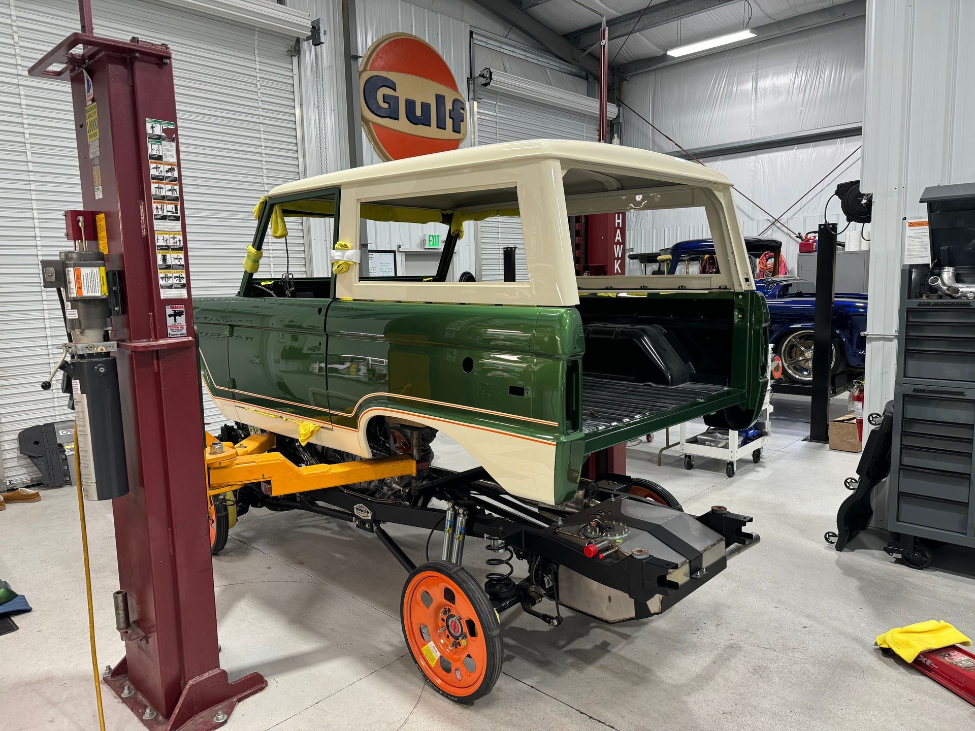A green and white van is sitting on a lift in a garage.