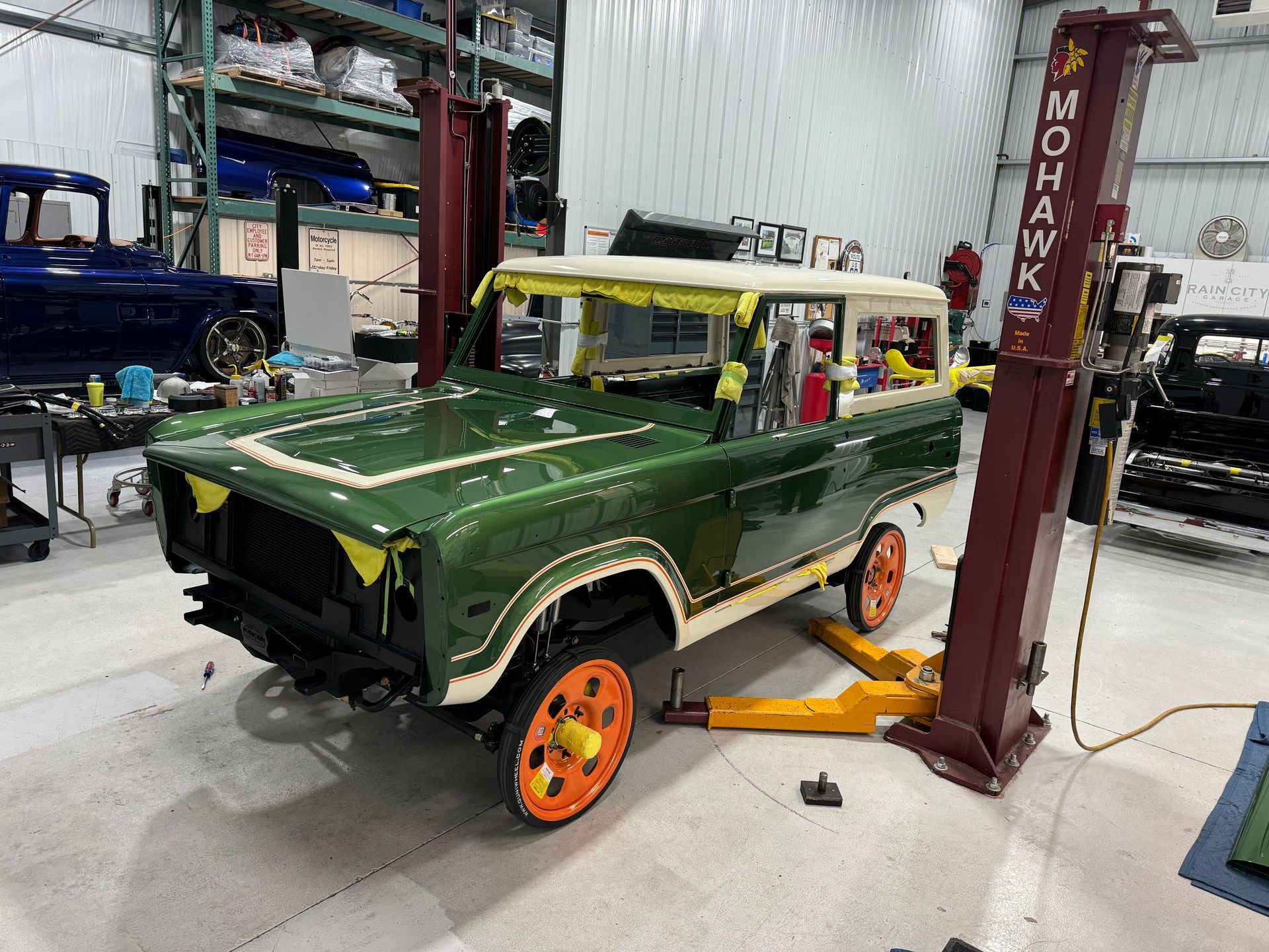 A green jeep is sitting on a lift in a garage.