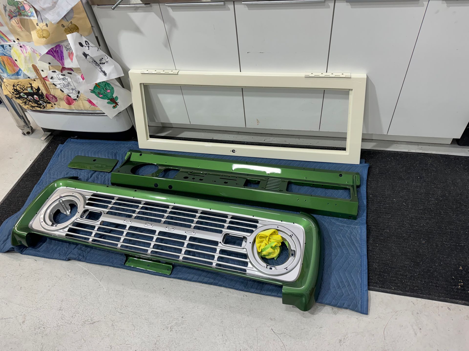 A green grille is sitting on a blue mat next to a window frame.