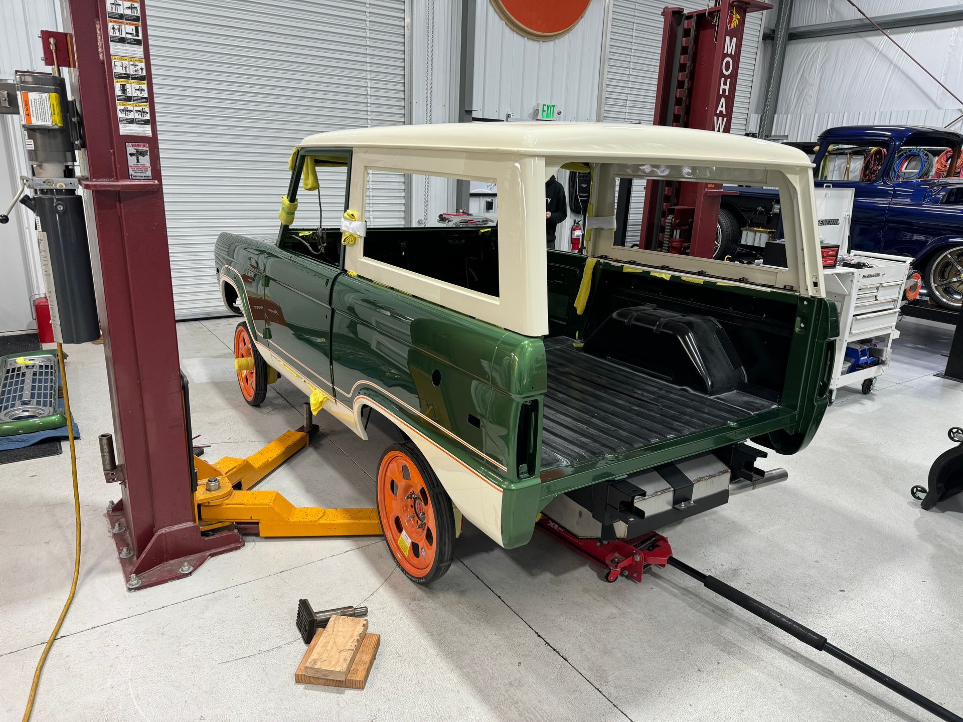 A green and white van is sitting on a lift in a garage.