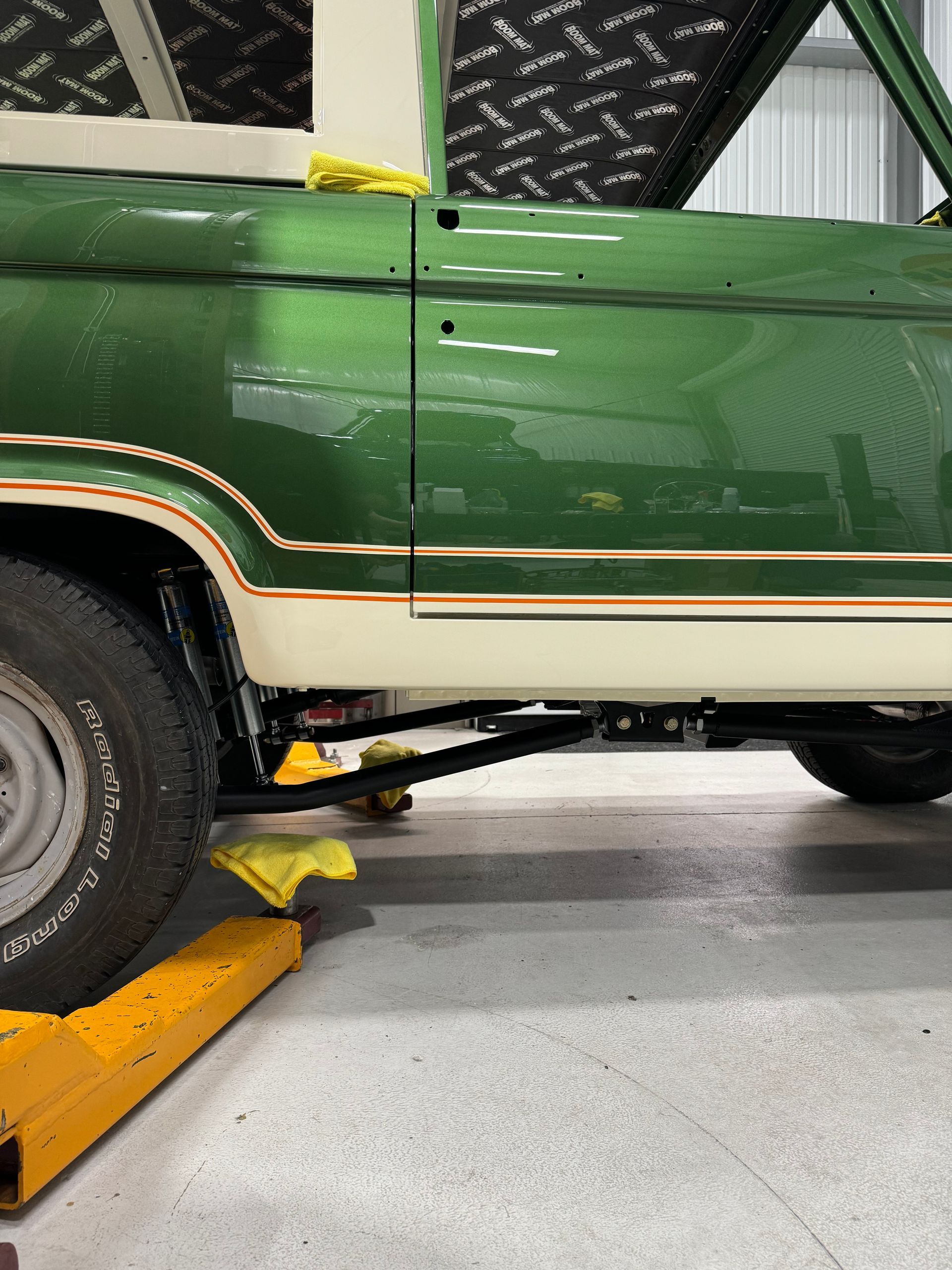 A green truck is sitting on a yellow ramp in a garage