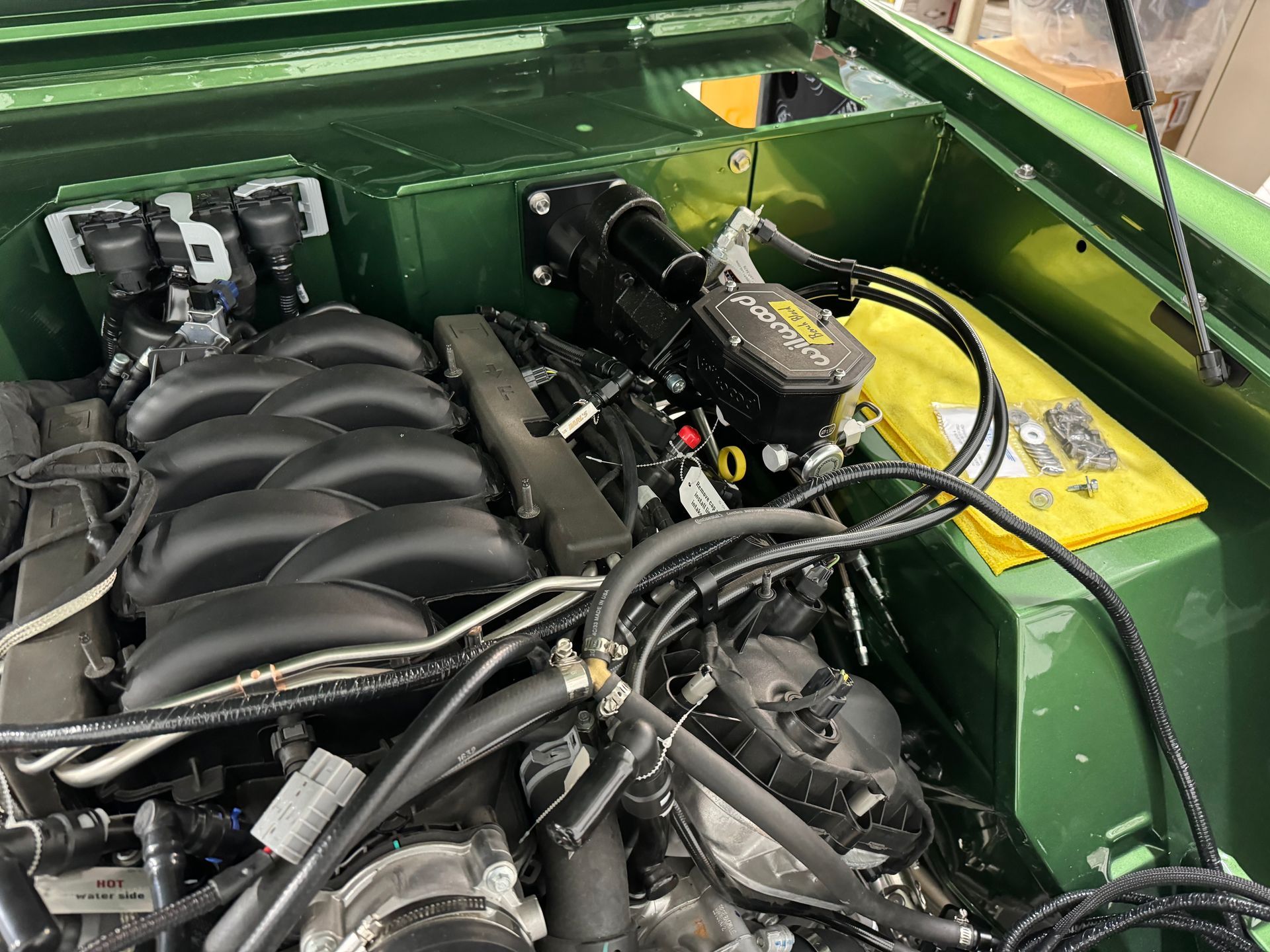 A close up of a green car engine with a yellow battery