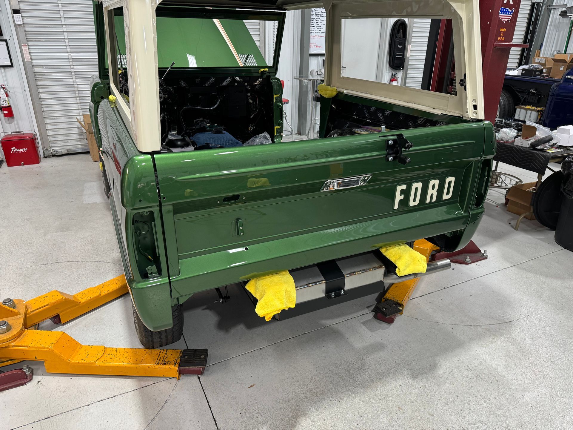 A green ford truck is sitting on a lift in a garage.