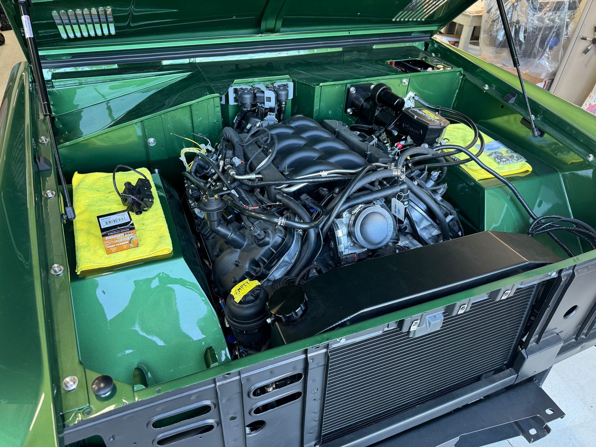 A green car with the hood open and the engine visible.