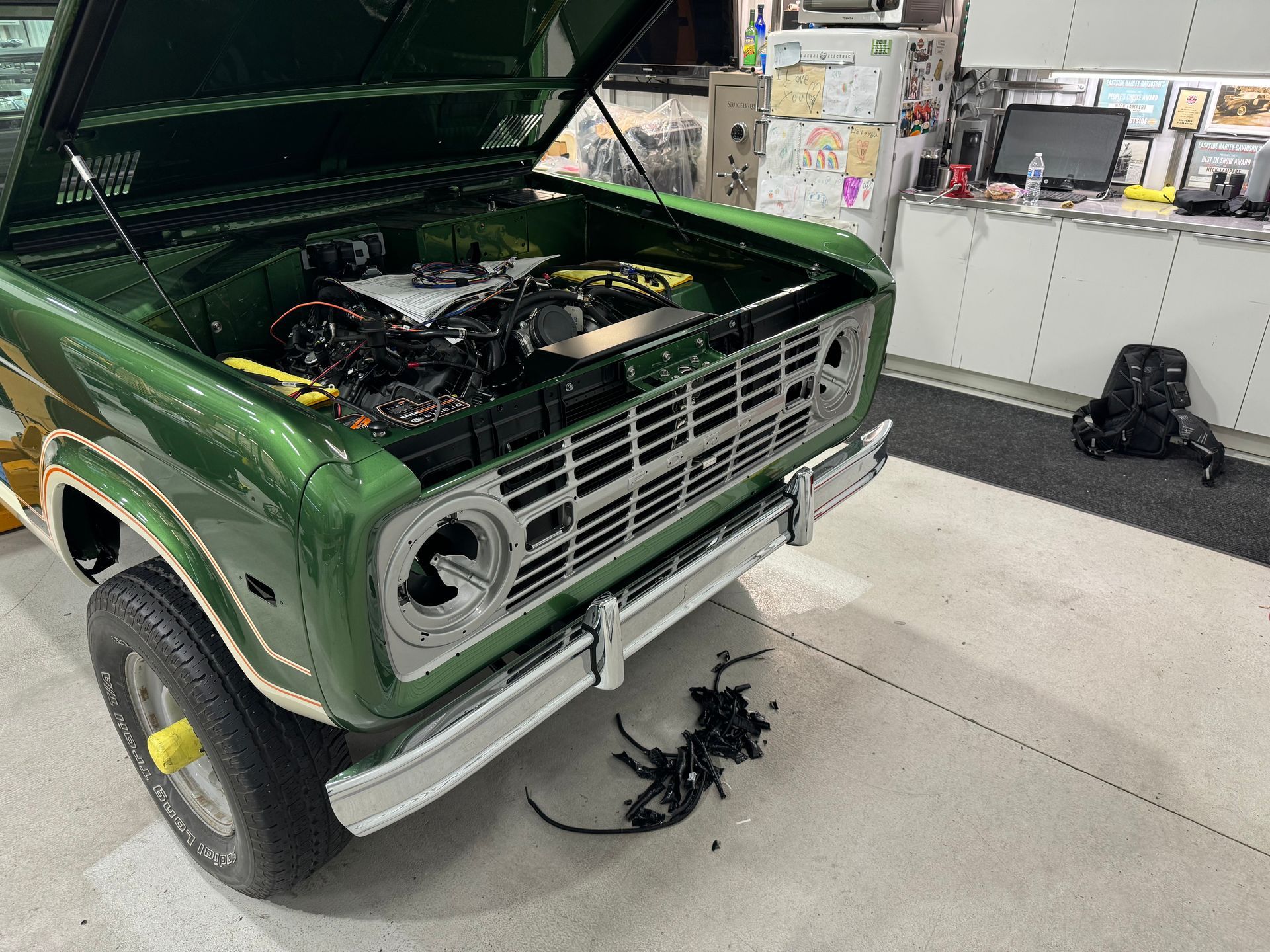 A green truck with the hood up is sitting in a garage.
