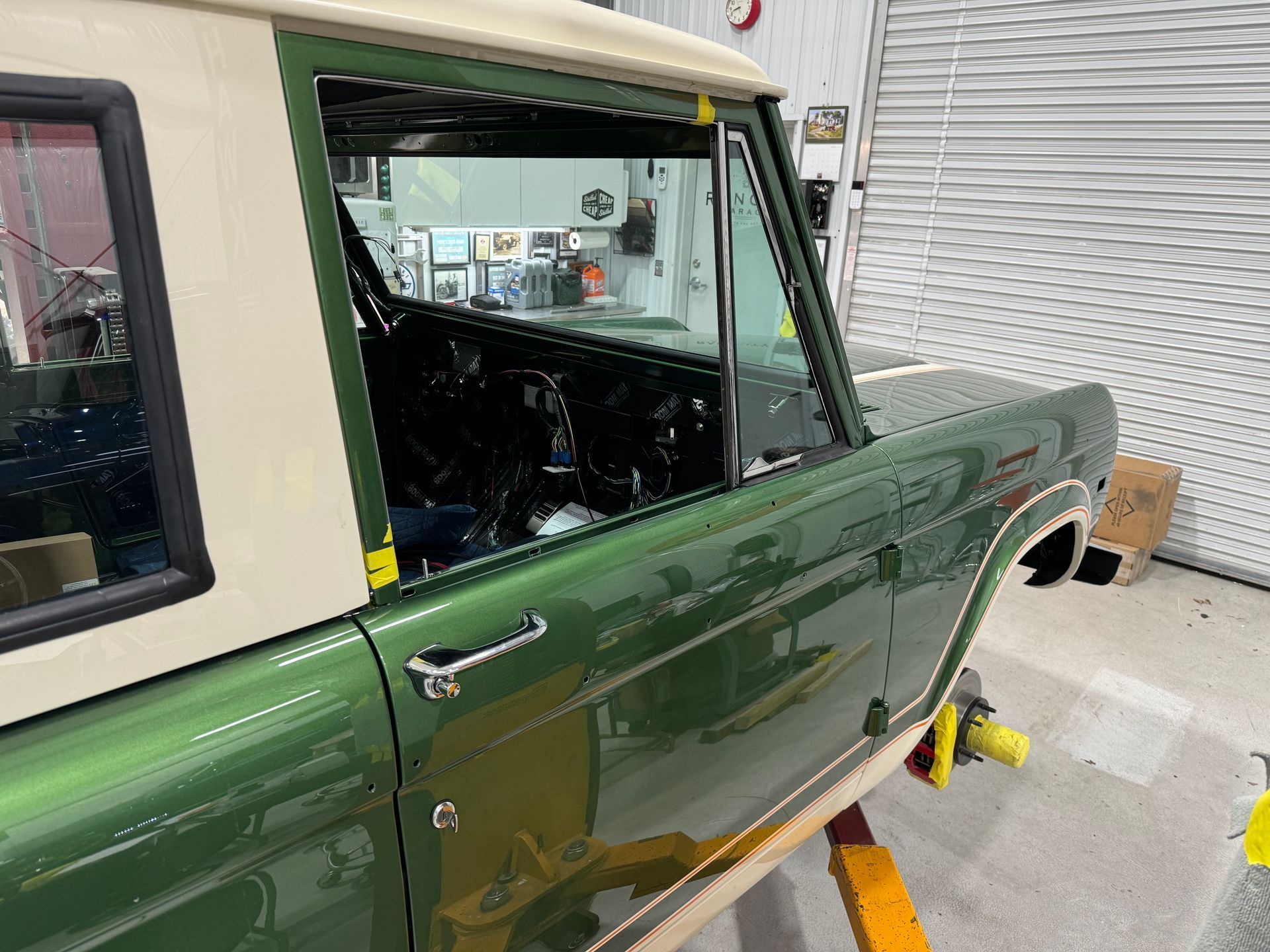 A green and white jeep is parked in a garage.