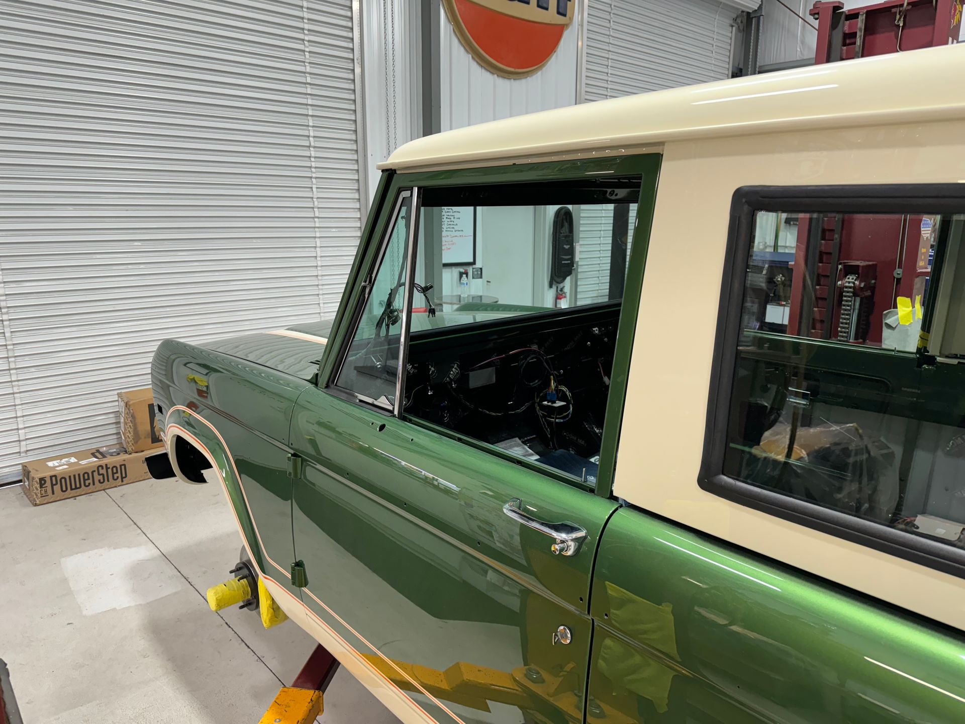 A green and white truck is parked in a garage.
