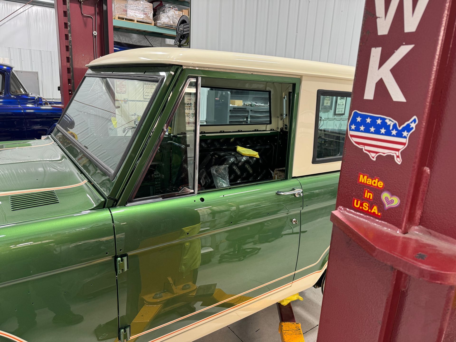 A green and white car is parked next to a sign that says made in the usa.
