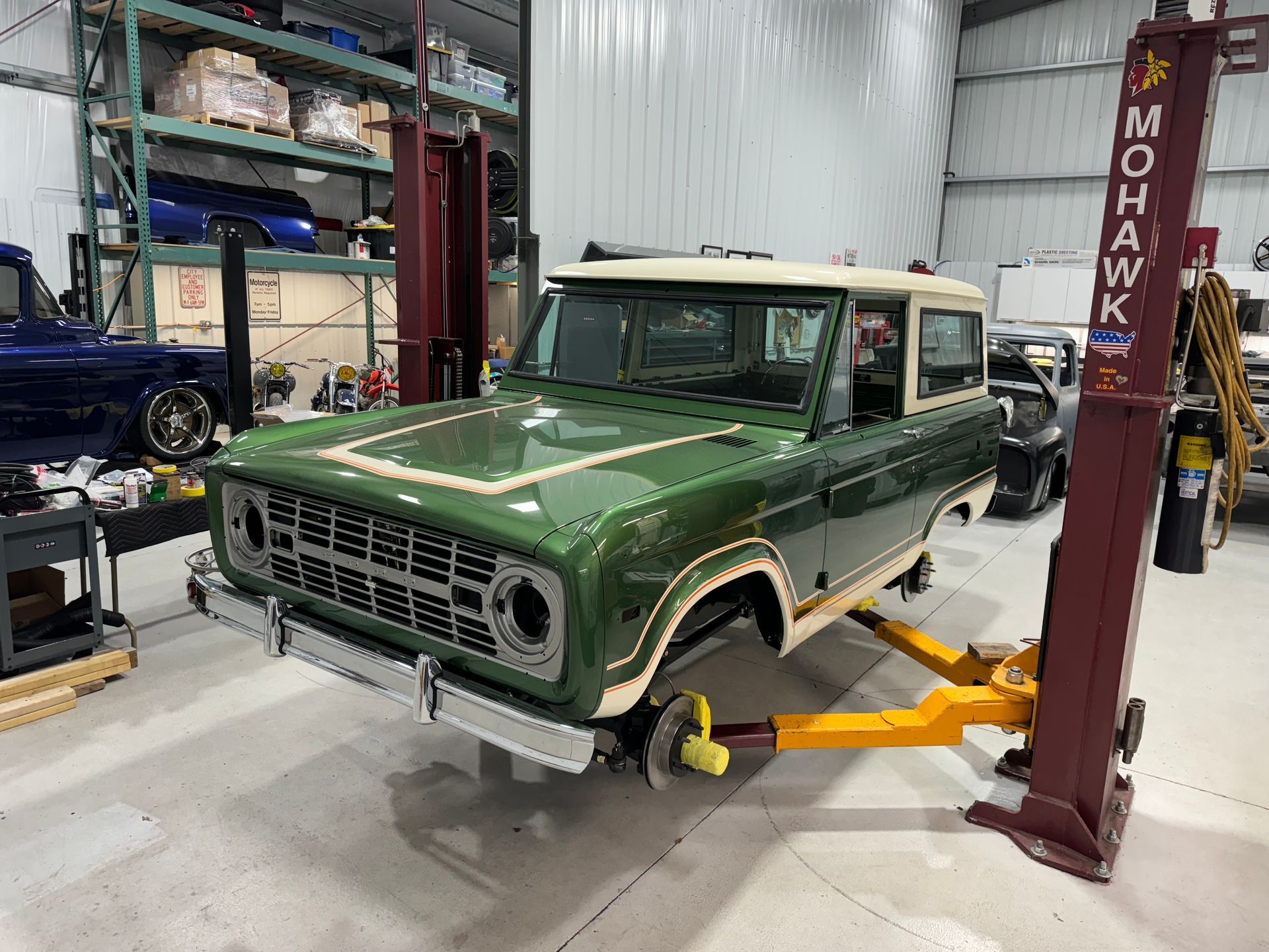 A green truck is sitting on a lift in a garage.