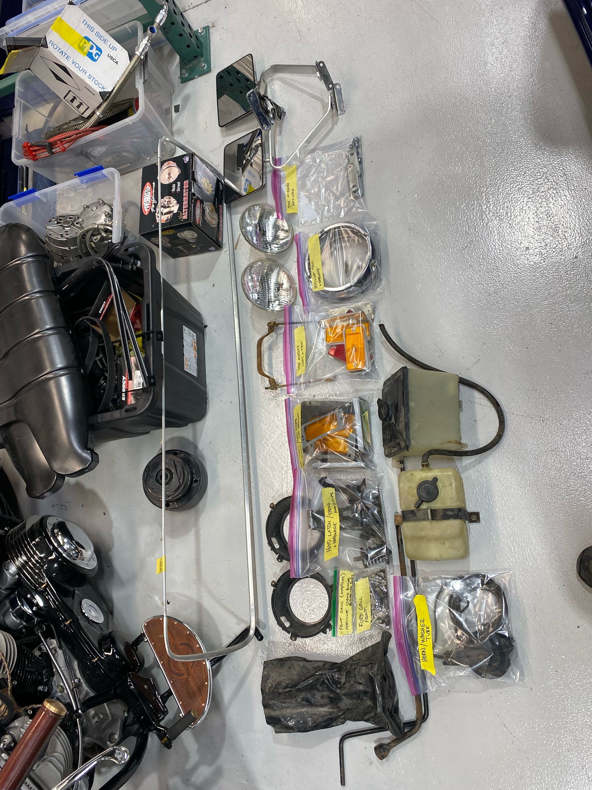 A bunch of motorcycle parts are sitting on the floor next to a motorcycle.