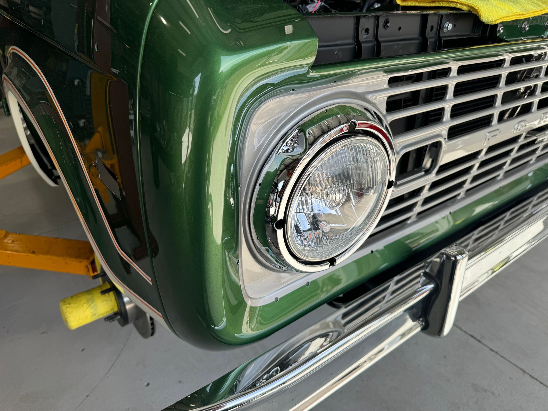 A green ford bronco is sitting on a lift in a garage.
