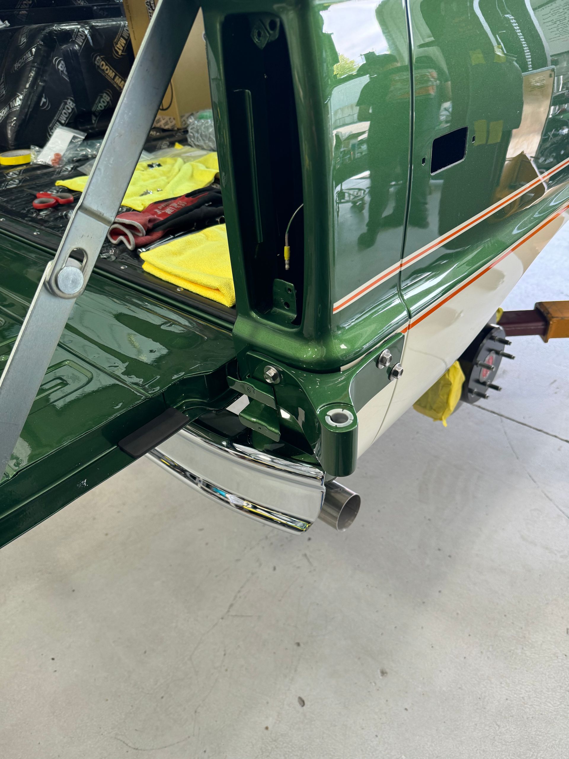 A green truck is sitting in a garage with the door open.