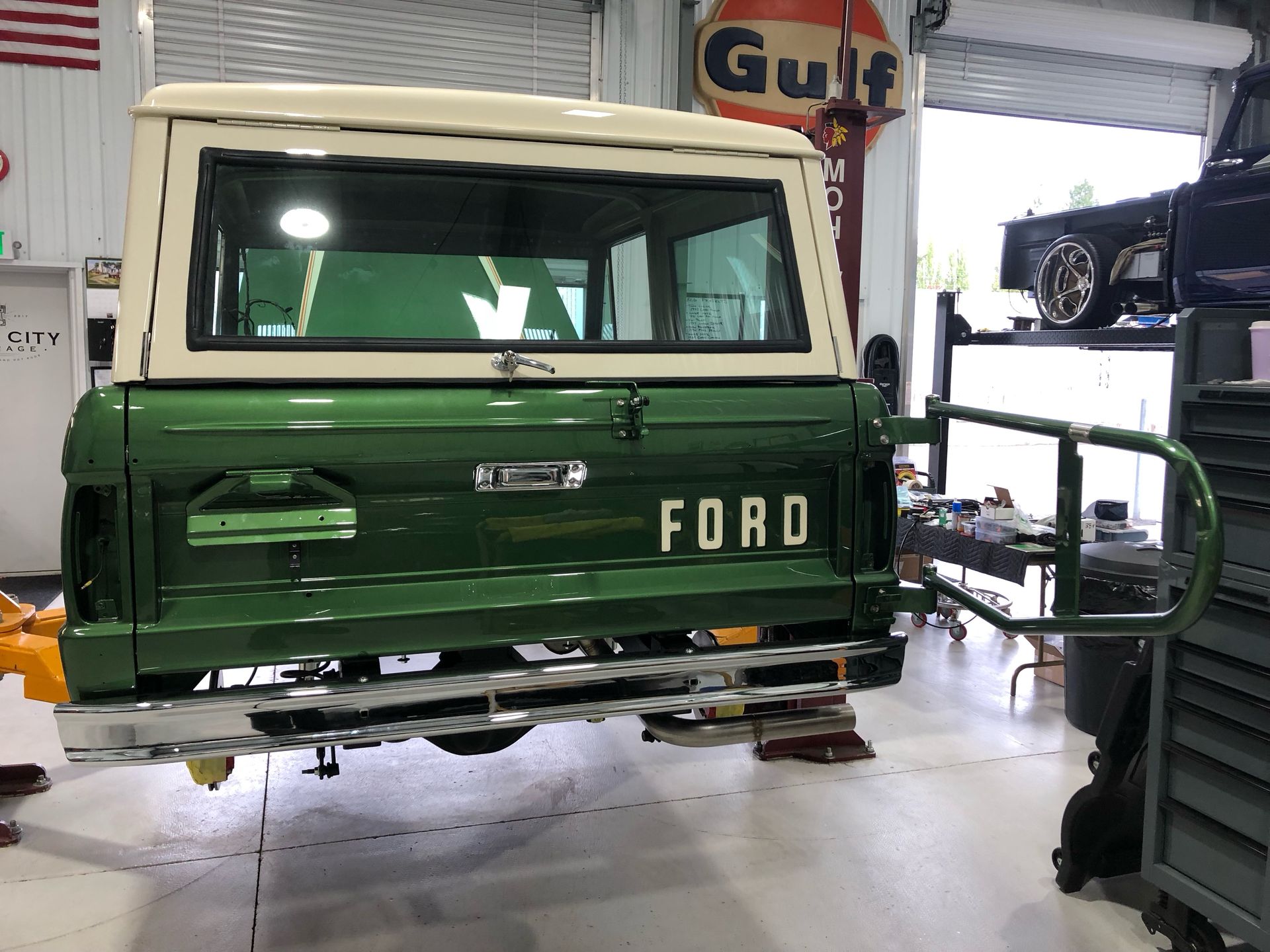 A green and white ford truck is parked in a garage.