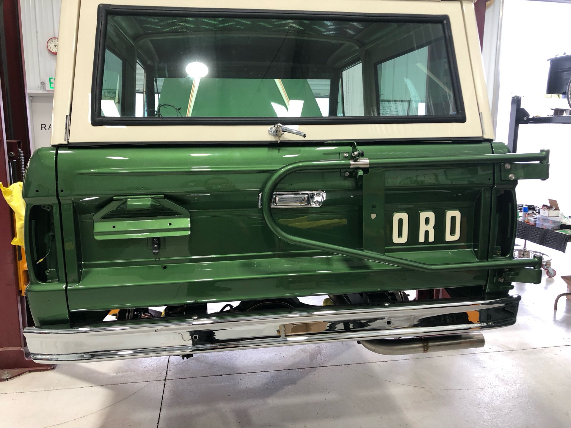 A green and white ford truck is parked in a garage.