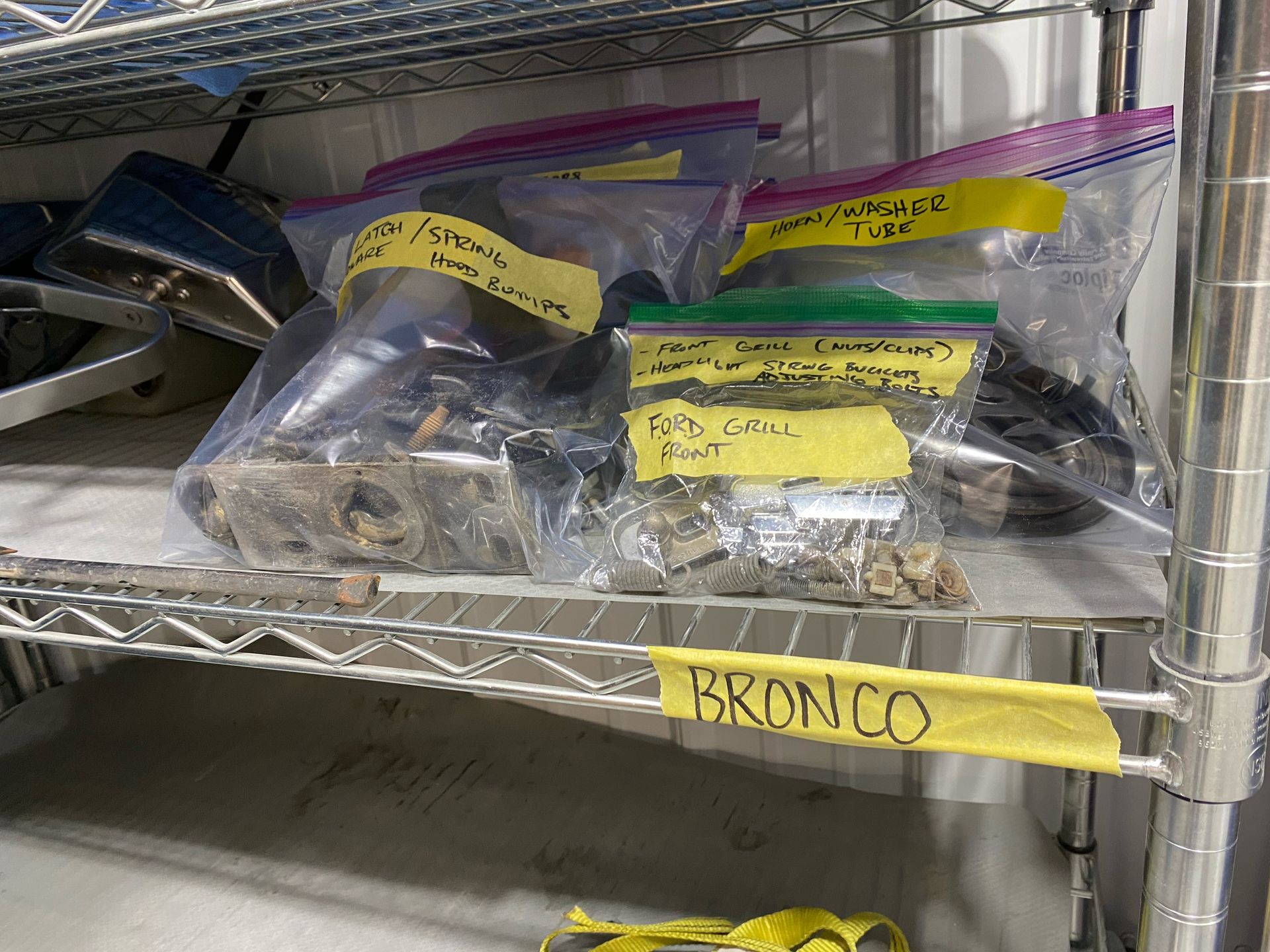 A shelf filled with bags of parts and a sign that says bronco.