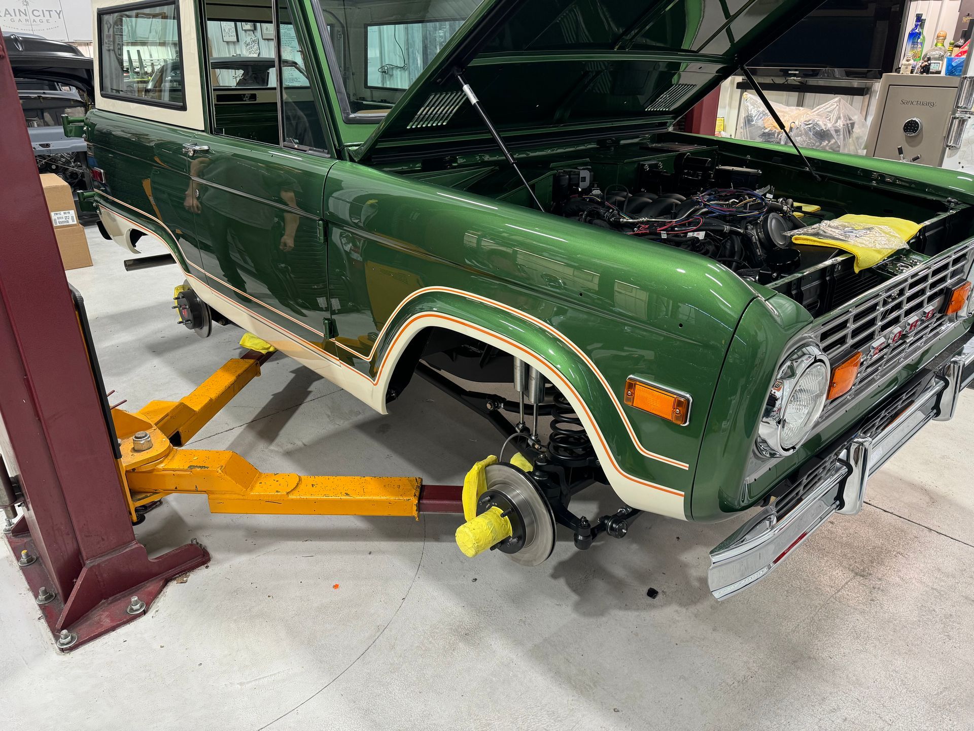 A green truck is sitting on a yellow lift in a garage.