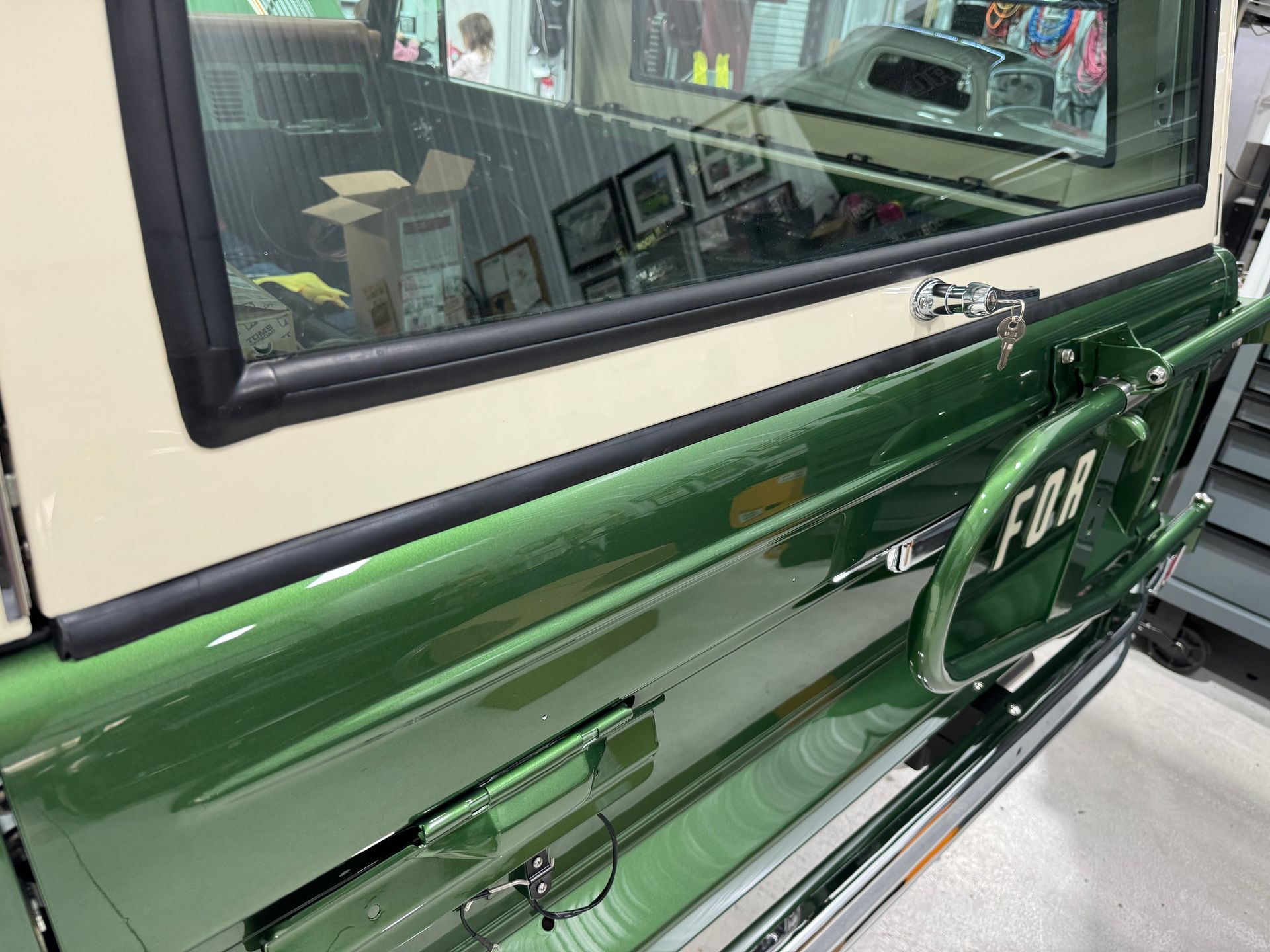 A green and white ford bronco is parked in a garage.