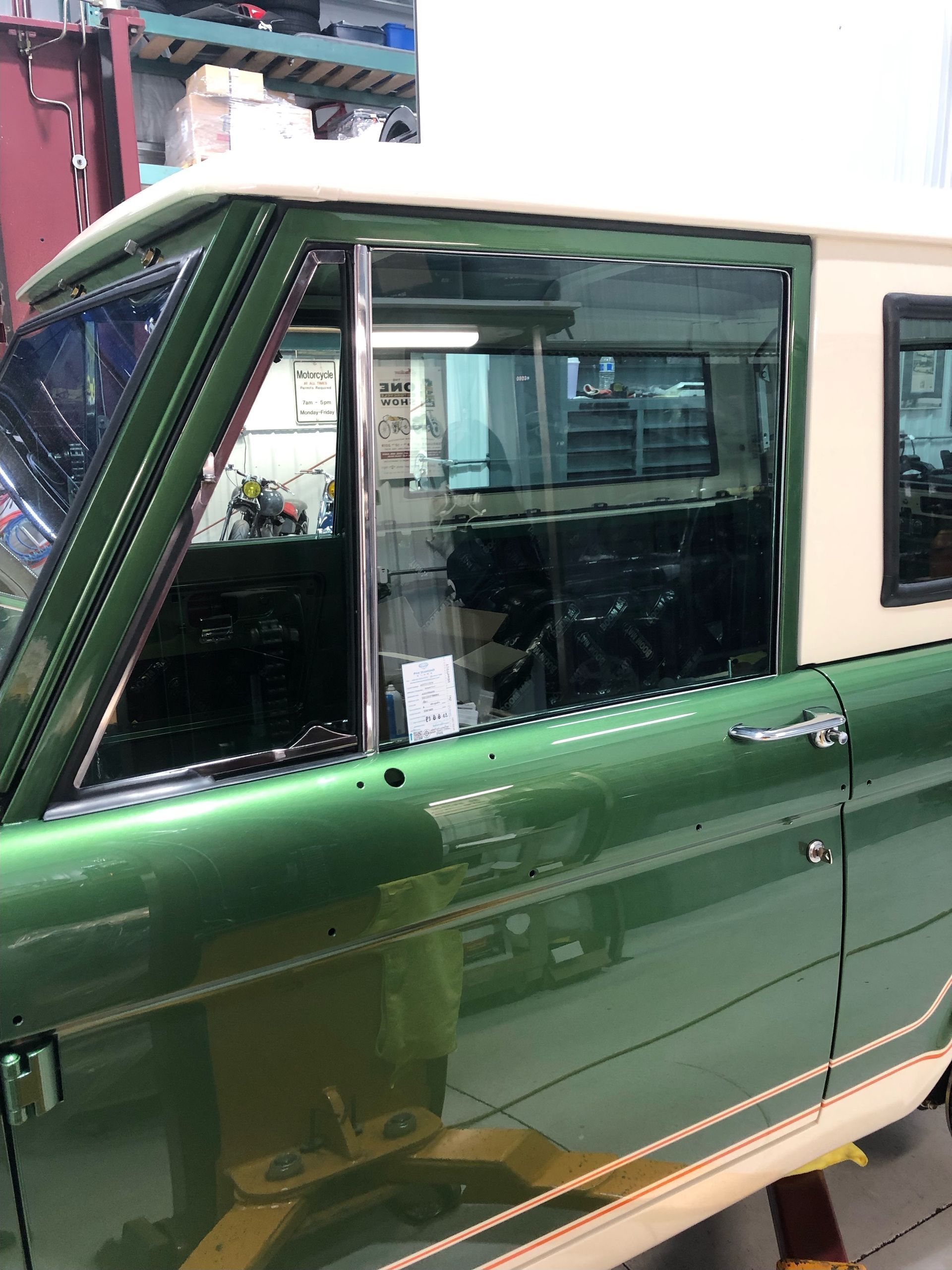 A green and white truck is parked in a garage.