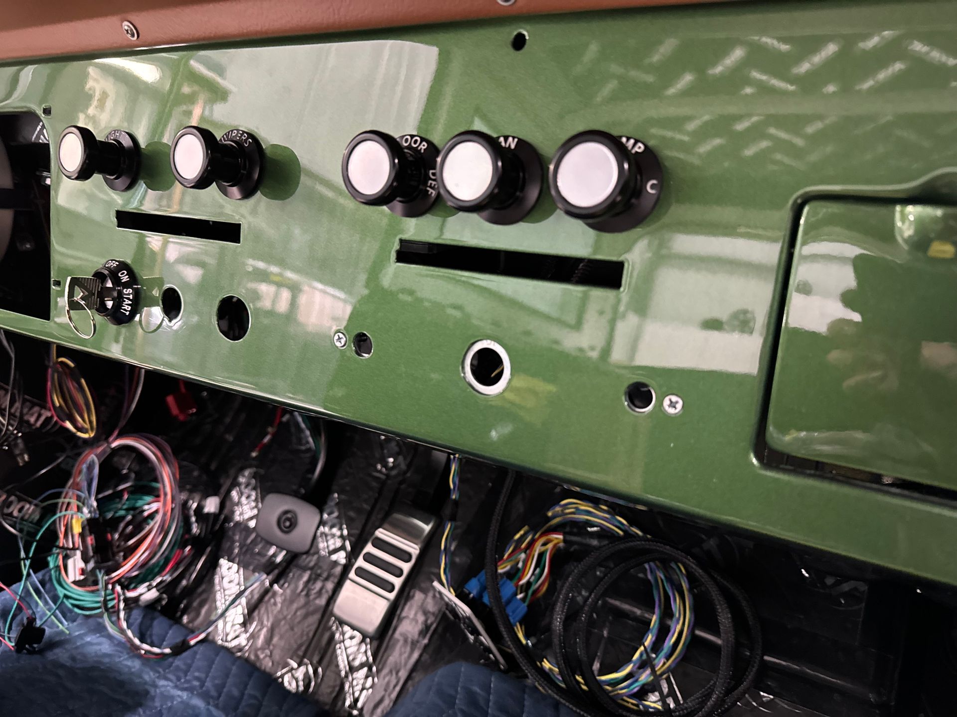 A green dashboard with a lot of wires and knobs