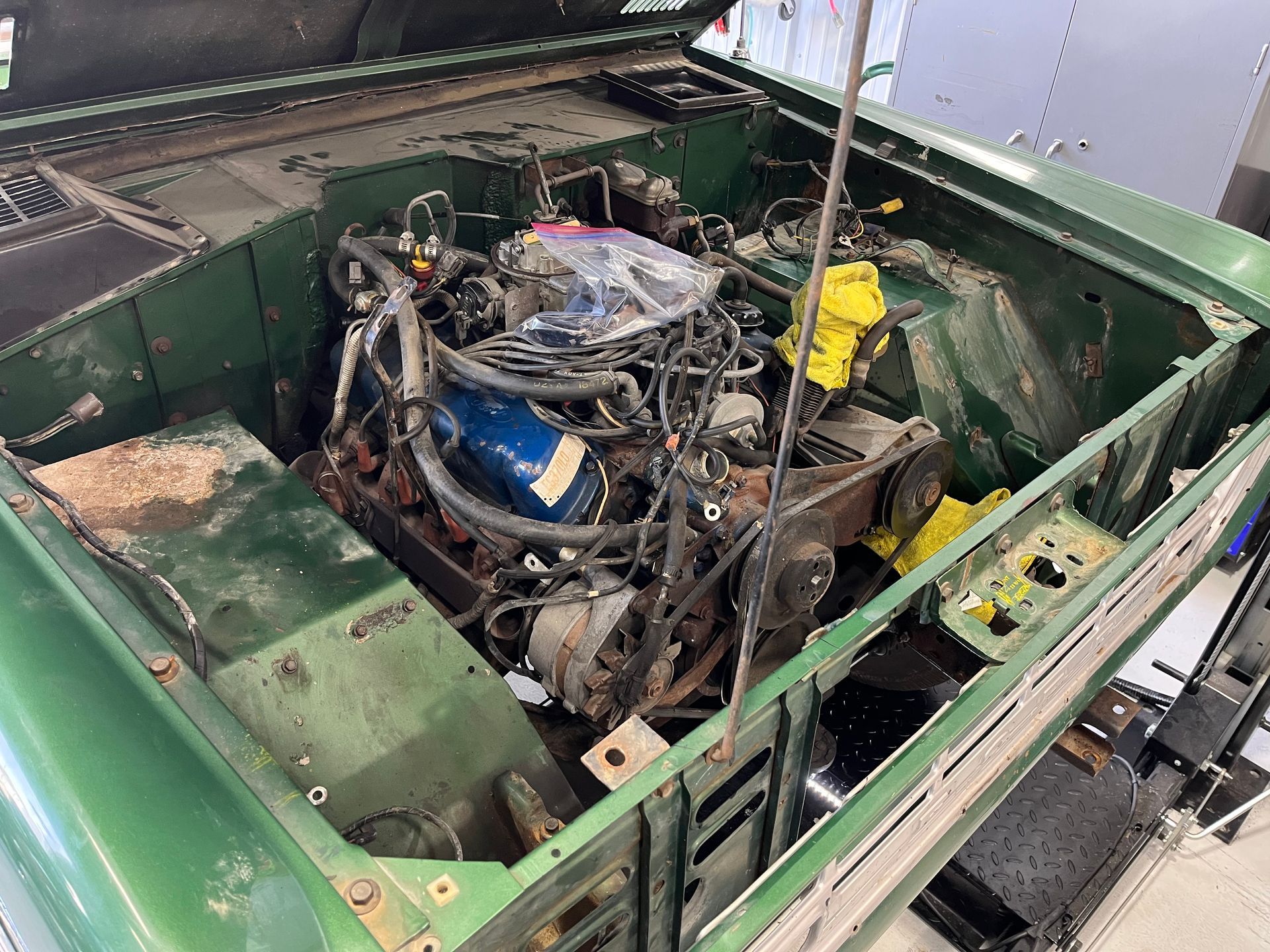 A green car with the hood open and the engine visible.