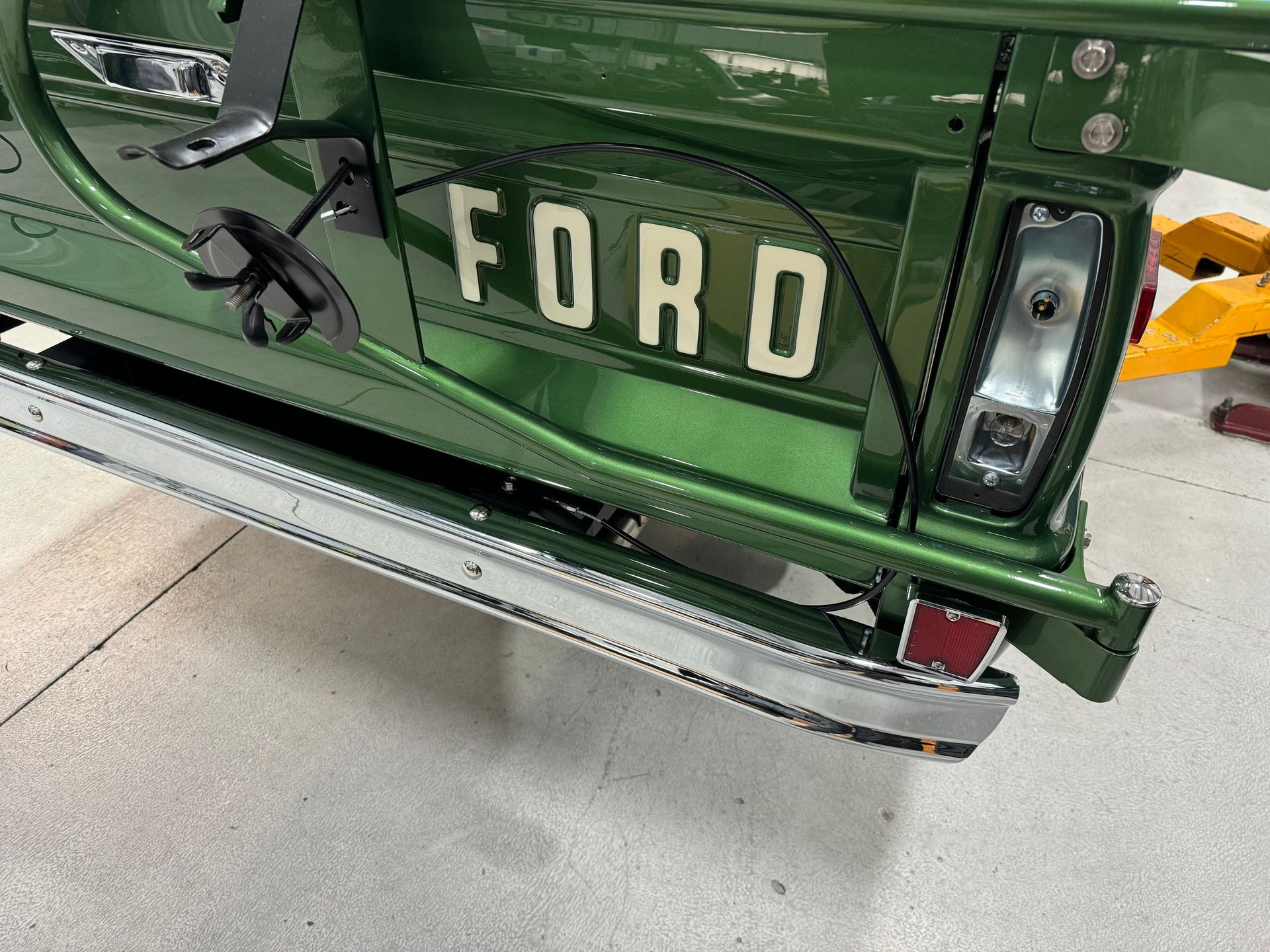 A green ford truck is parked in a garage.