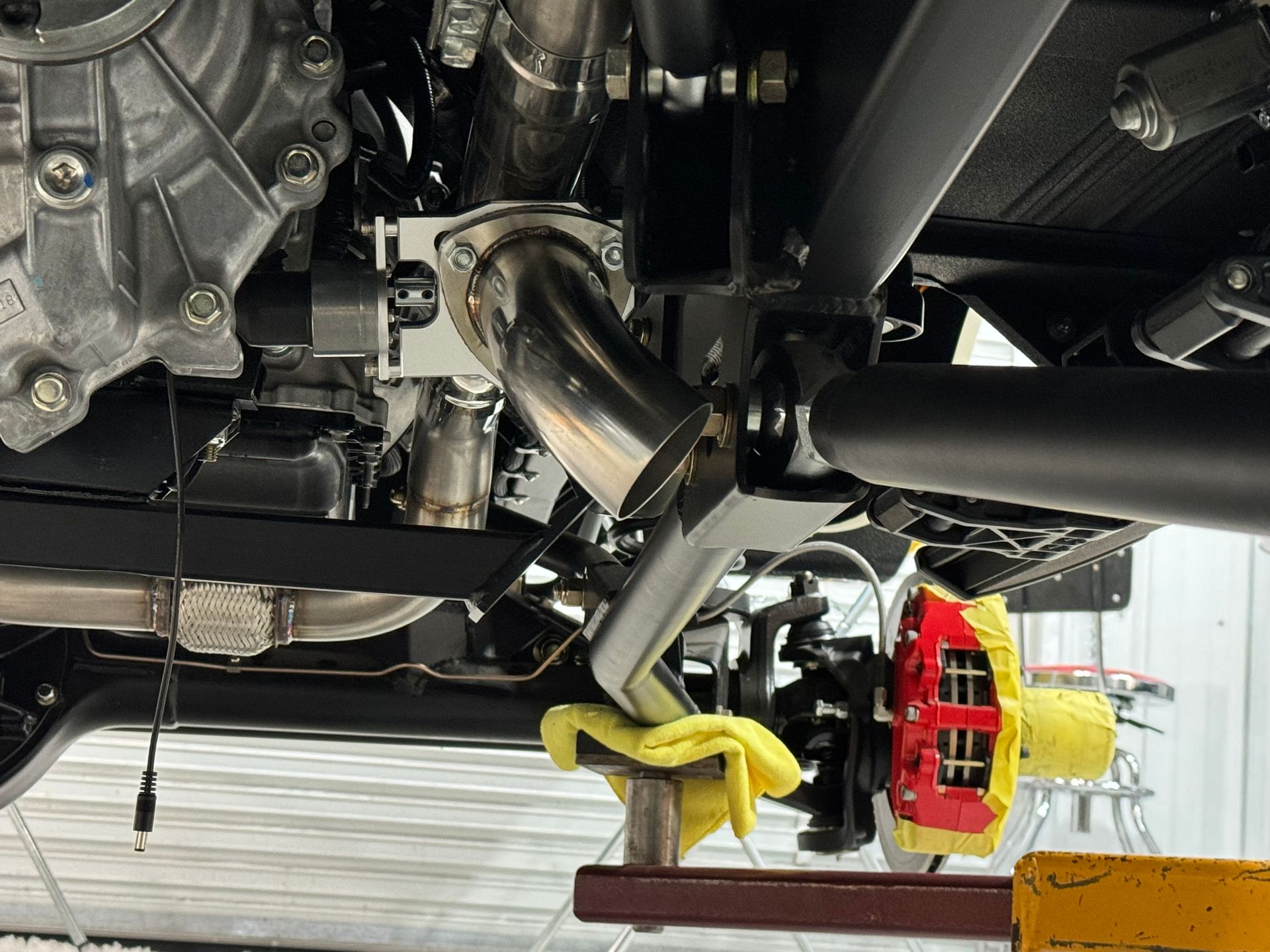 A close up of the underside of a car with a red brake caliper