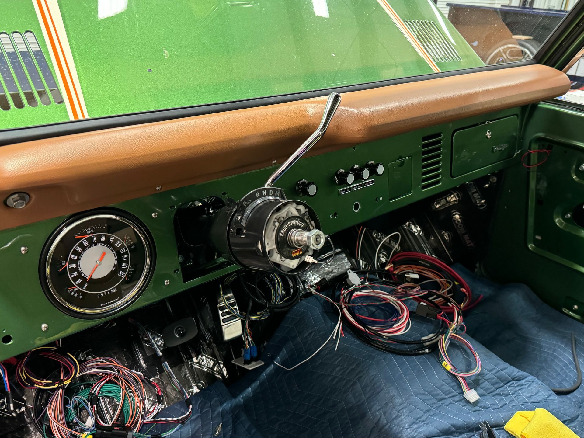 The dashboard of a green car with a lot of wires coming out of it.