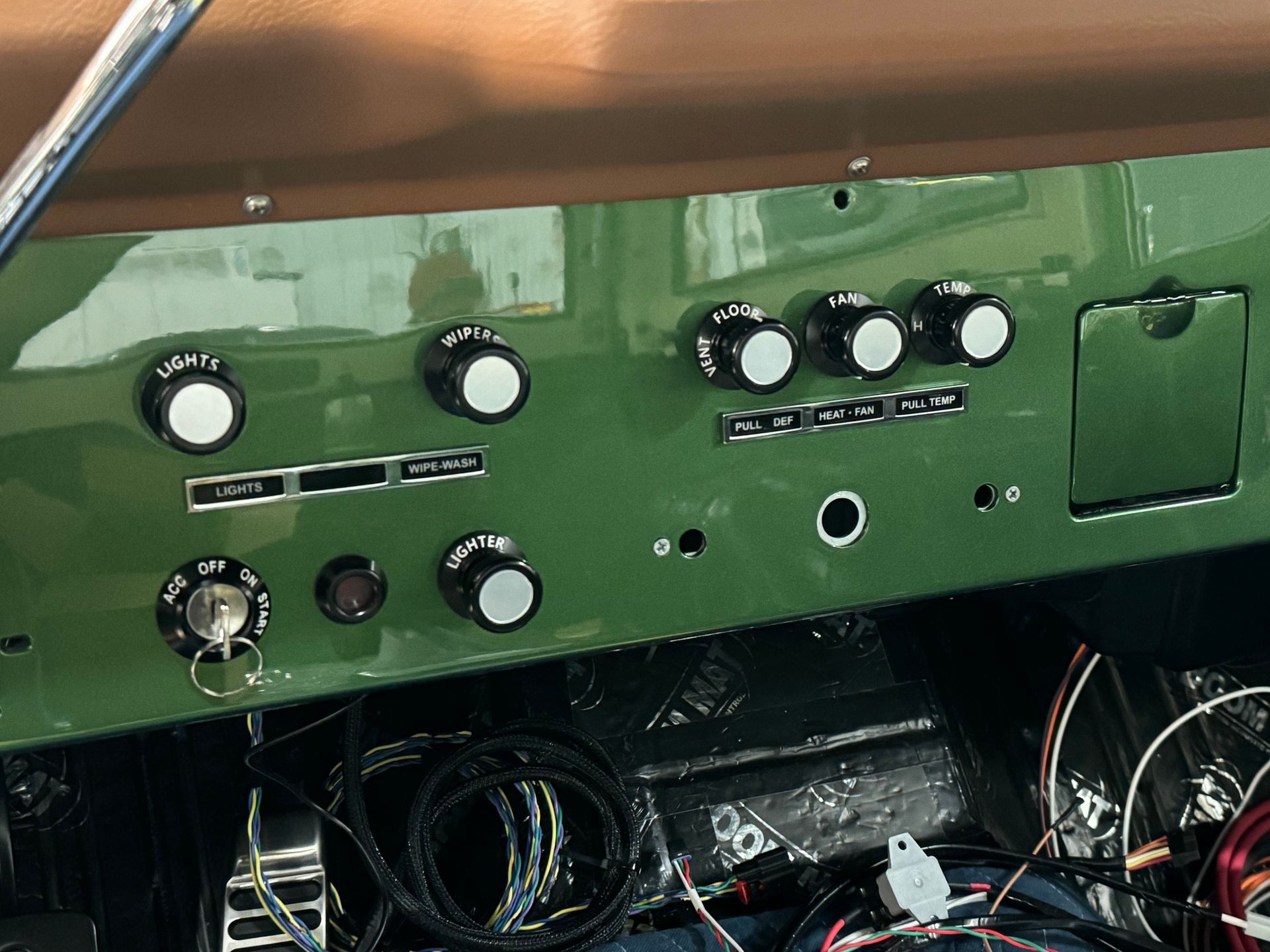 The dashboard of a green jeep with buttons and knobs