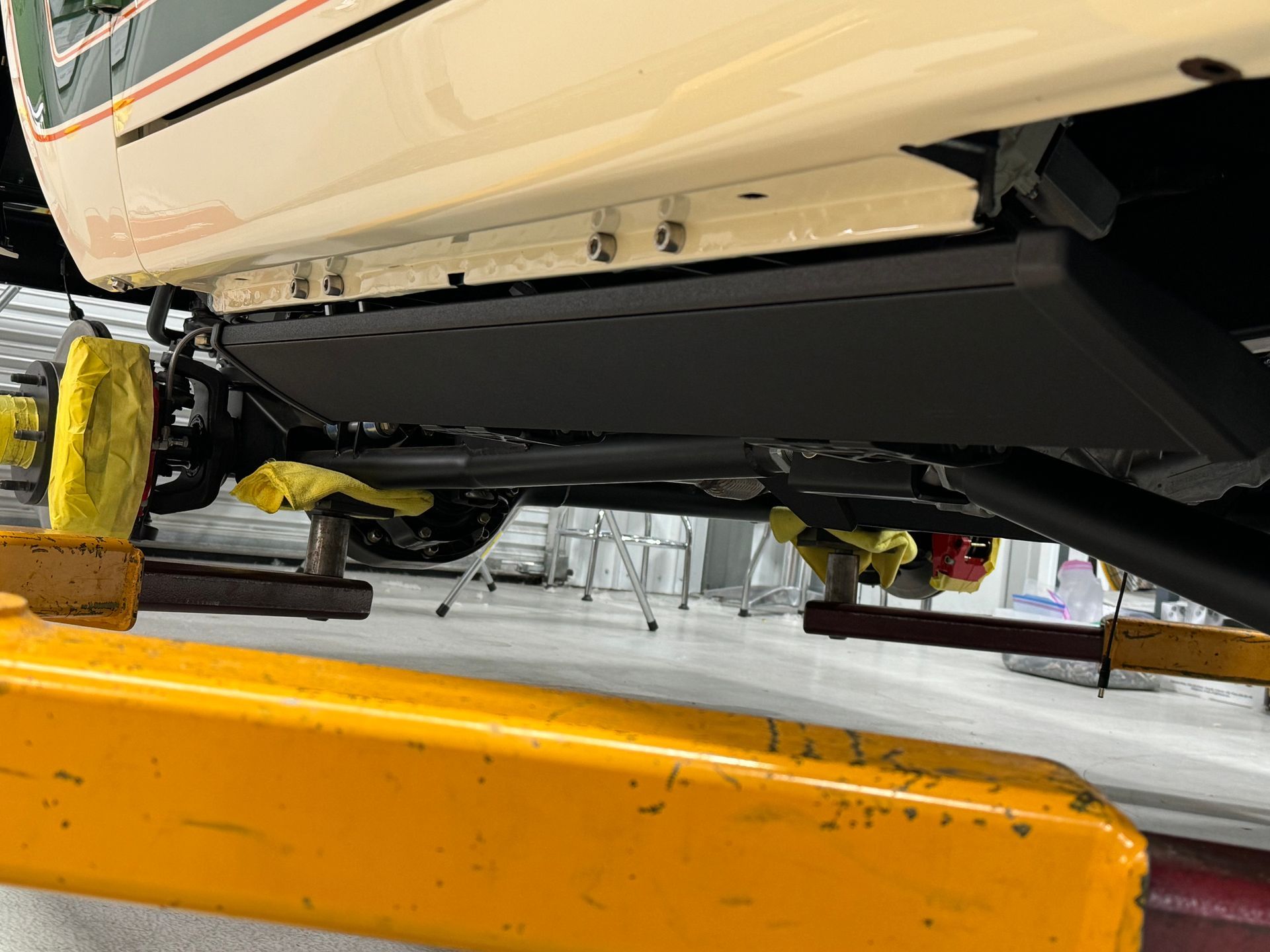 A car is sitting on a yellow lift in a garage.