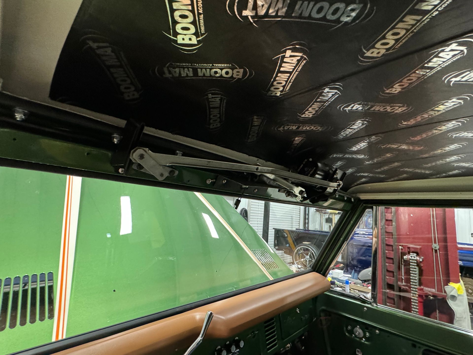 The inside of a green car with a boom mat on the ceiling.