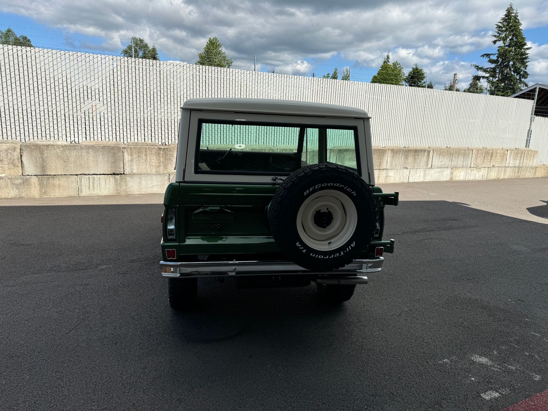 A green jeep with a spare tire is parked in a parking lot.