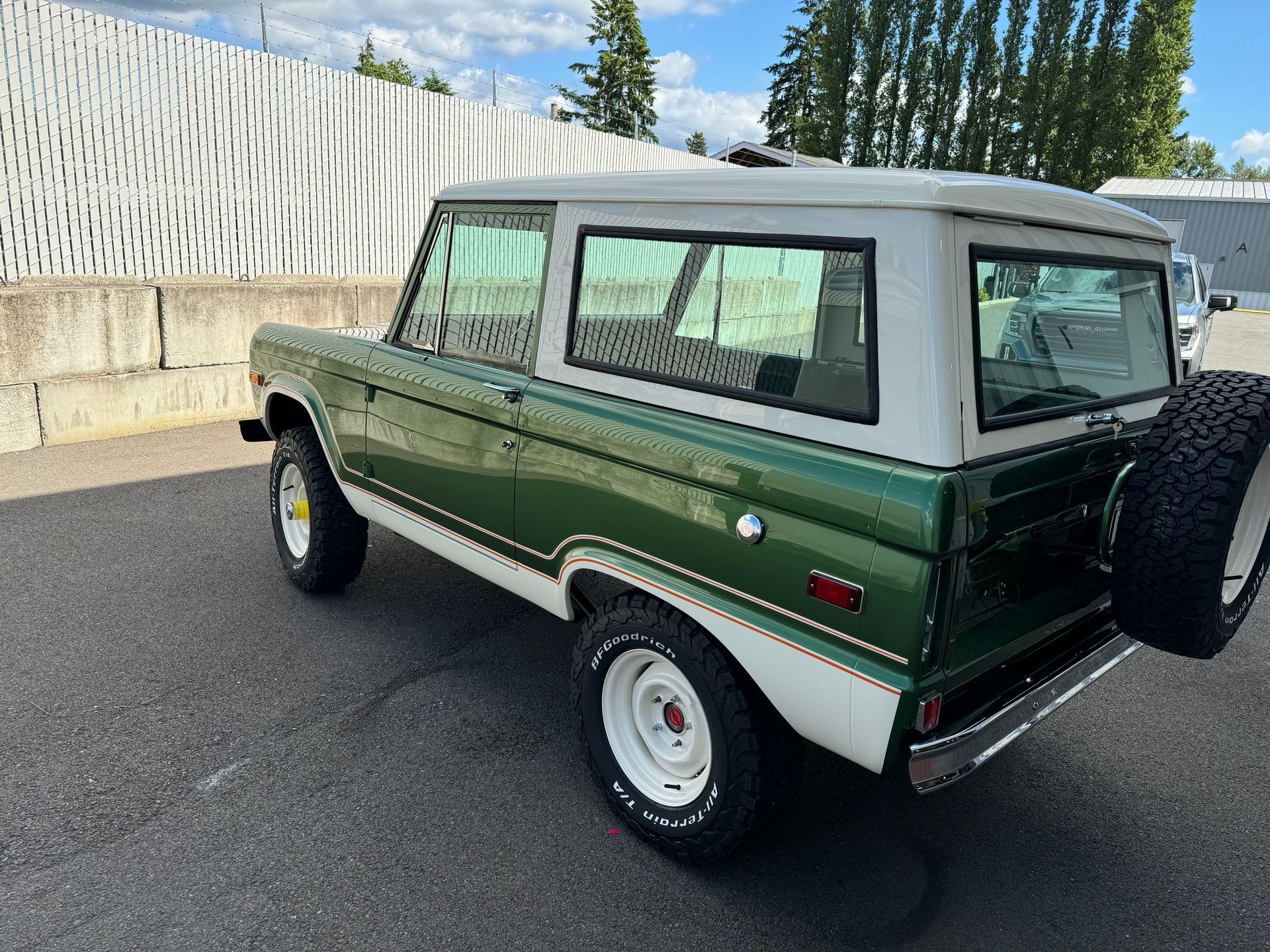 A green and white ford bronco is parked in a parking lot.