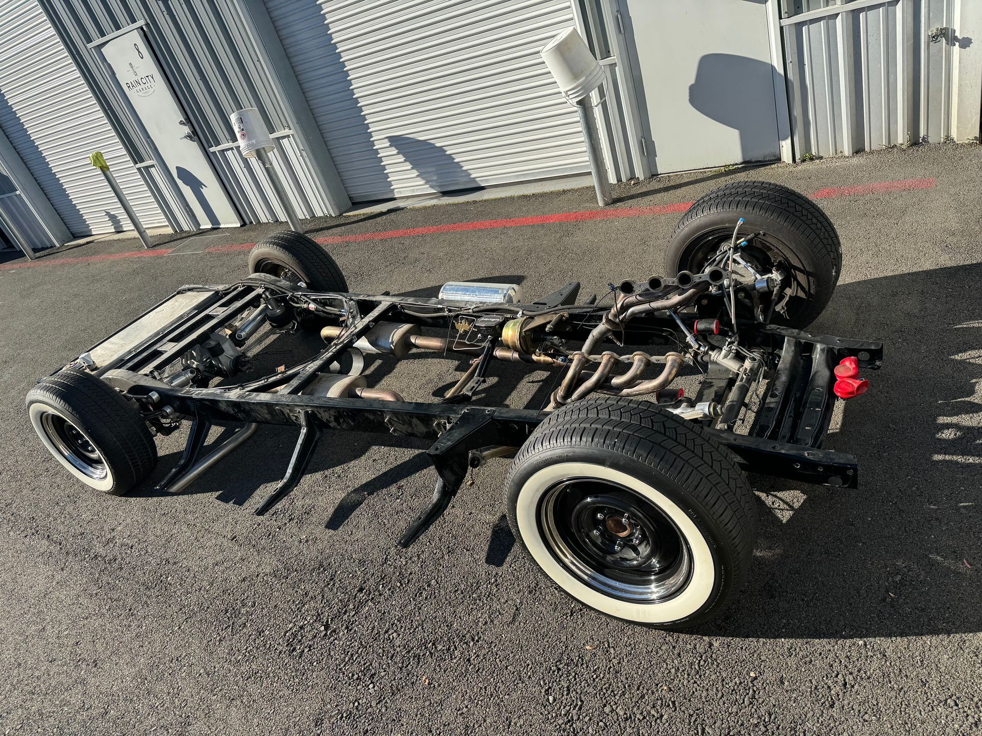 A truck chassis is laying on the ground in front of a building.