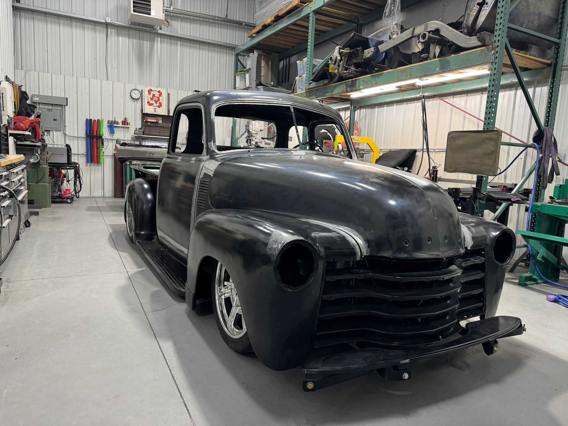 An old black truck is parked in a garage.