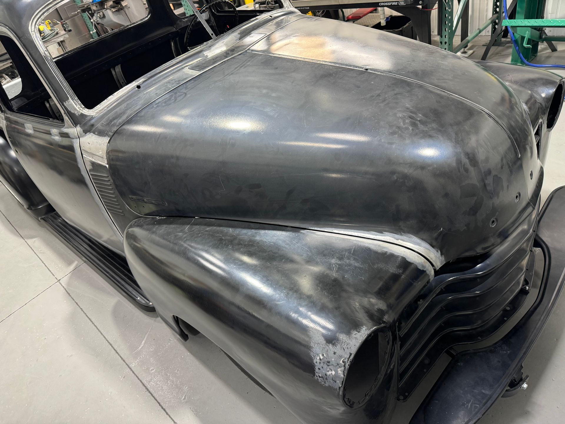 An old car is sitting in a garage without a hood.